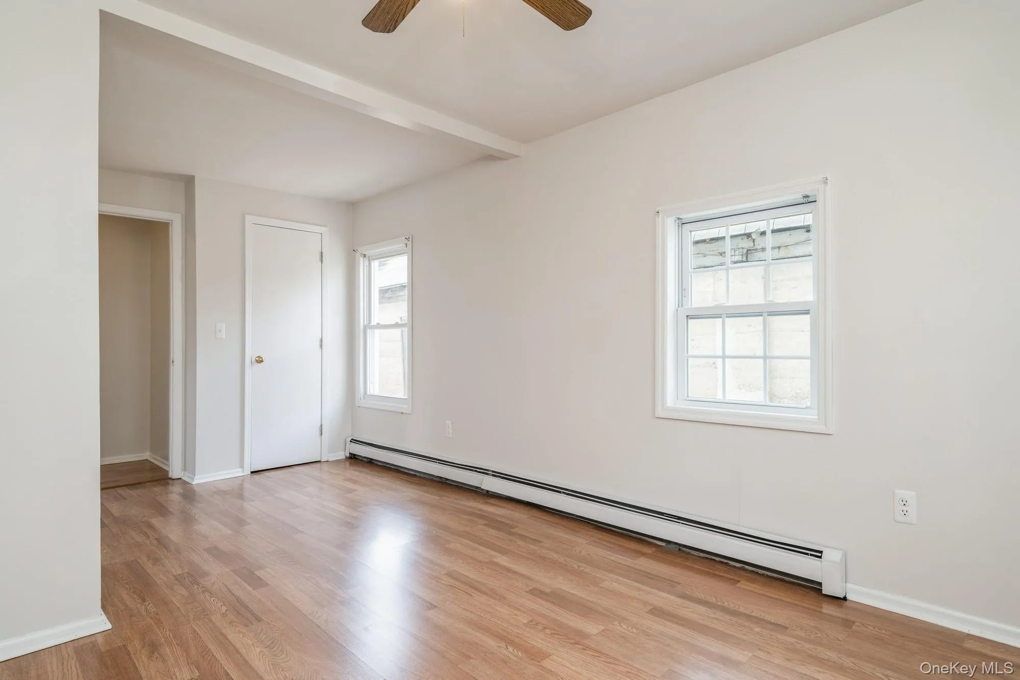 Unfurnished bedroom featuring a baseboard heating unit, light wood-style floors, beamed ceiling, and ceiling fan Unfurnished bedroom featuring a baseboard heating unit, light wood-style floors, beamed ceiling, and ceiling fan