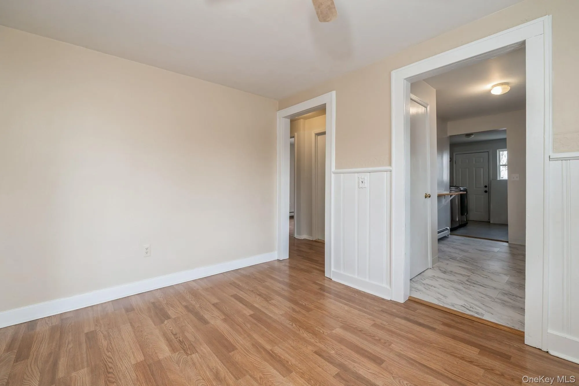 Dining room with light wood-style floors, ceiling fan, wainscoting, and baseboard heating Dining room with light wood-style floors, ceiling fan, wainscoting, and baseboard heating
