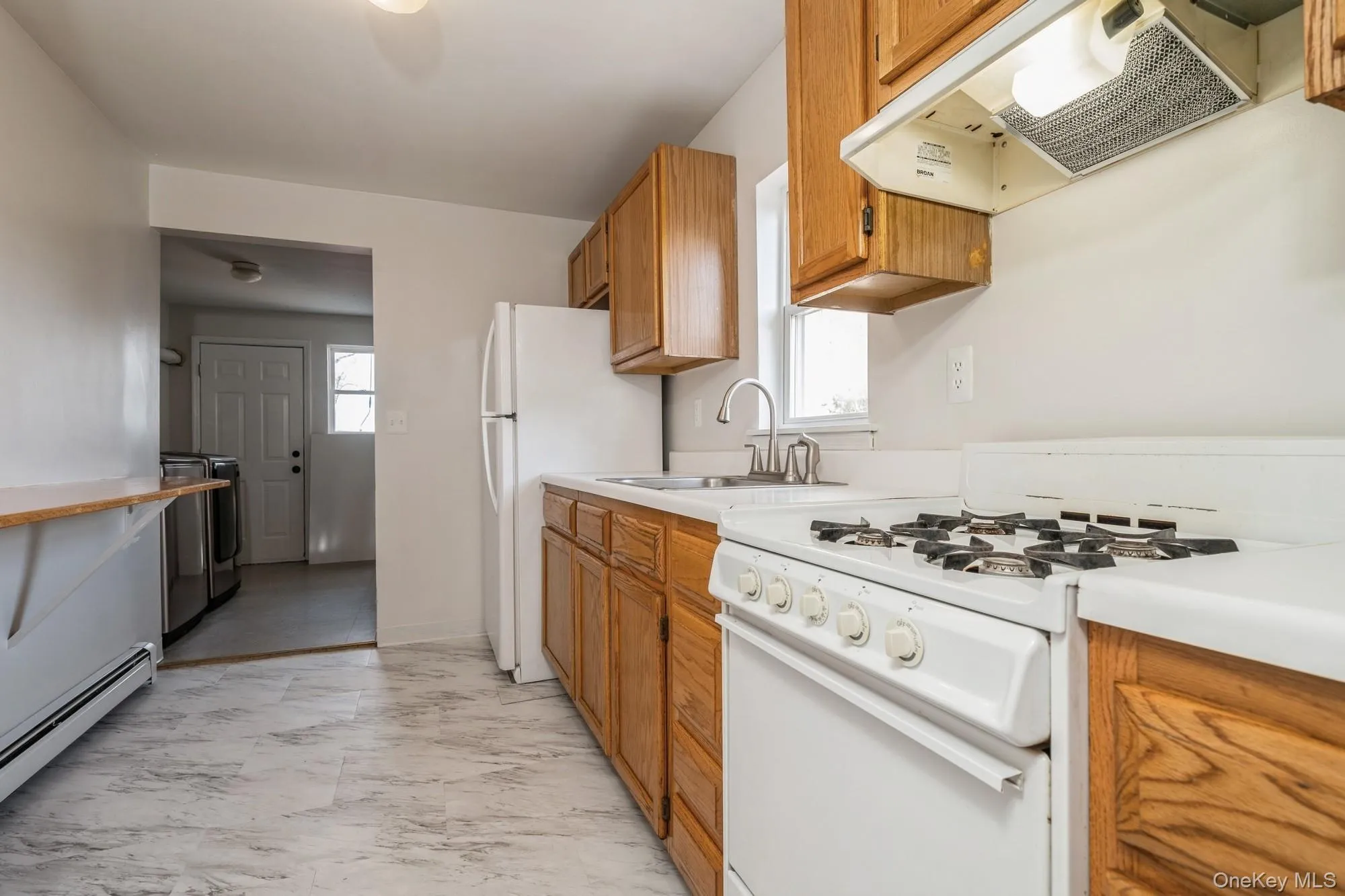 Kitchen with white appliances, light countertops, range hood, and healthy amount of natural light Kitchen with white appliances, light countertops, range hood, and healthy amount of natural light