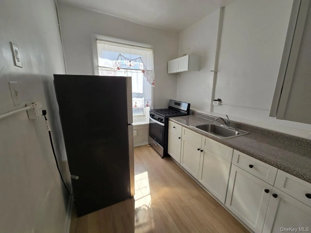 Kitchen featuring white cabinetry, appliances with stainless steel finishes, light wood finished floors, and dark countertops Kitchen featuring white cabinetry, appliances with stainless steel finishes, light wood finished floors, and dark countertops