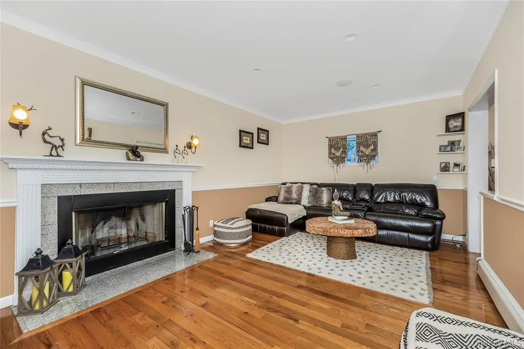 Living area with crown molding, wood finished floors, and a fireplace Living area with crown molding, wood finished floors, and a fireplace