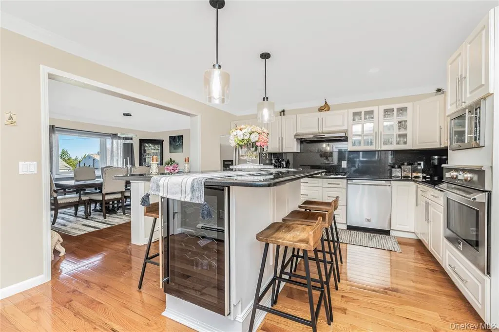 Kitchen featuring decorative backsplash, a kitchen bar, a center island, appliances with stainless steel finishes, and light wood-type flooring Kitchen featuring decorative backsplash, a kitchen bar, a center island, appliances with stainless steel finishes, and light wood-type flooring