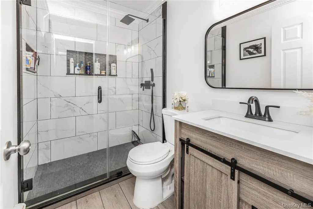 Full bath featuring vanity and a marble finish shower Full bath featuring vanity and a marble finish shower