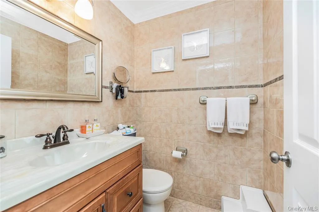Full bath with vanity, tile walls, and crown molding Full bath with vanity, tile walls, and crown molding