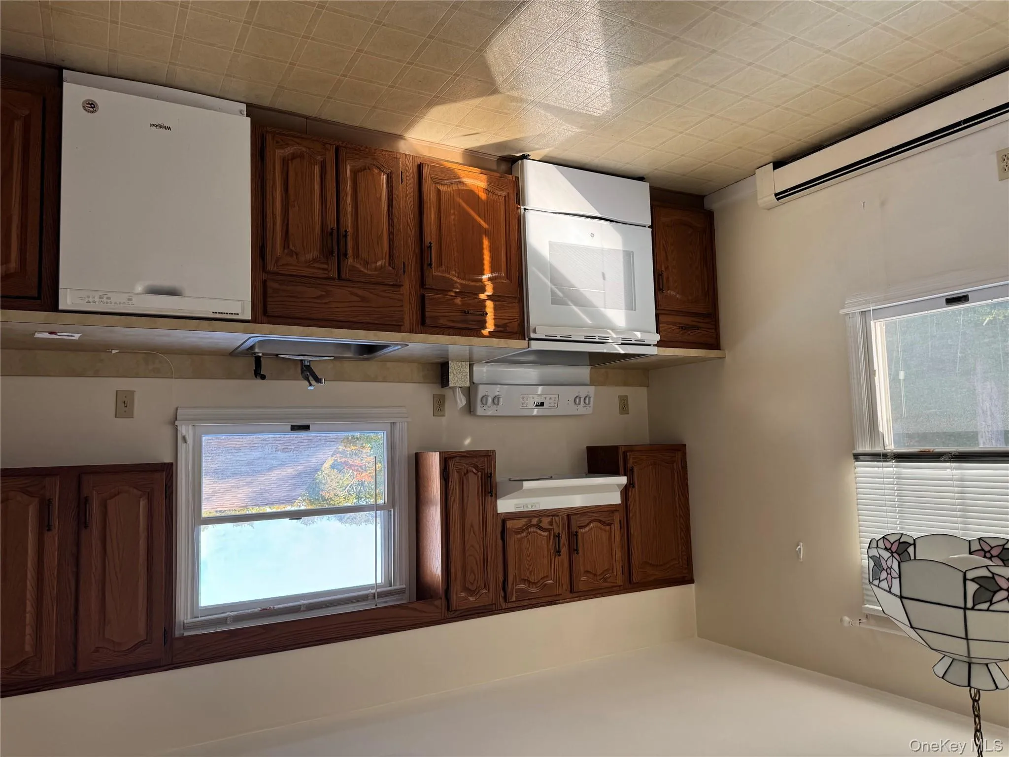 Kitchen featuring white range oven, dishwashing machine, light countertops, and a baseboard heating unit Kitchen featuring white range oven, dishwashing machine, light countertops, and a baseboard heating unit
