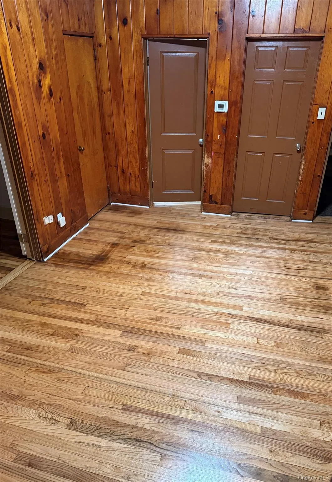 Entryway with light wood-type flooring and wood walls Entryway with light wood-type flooring and wood walls