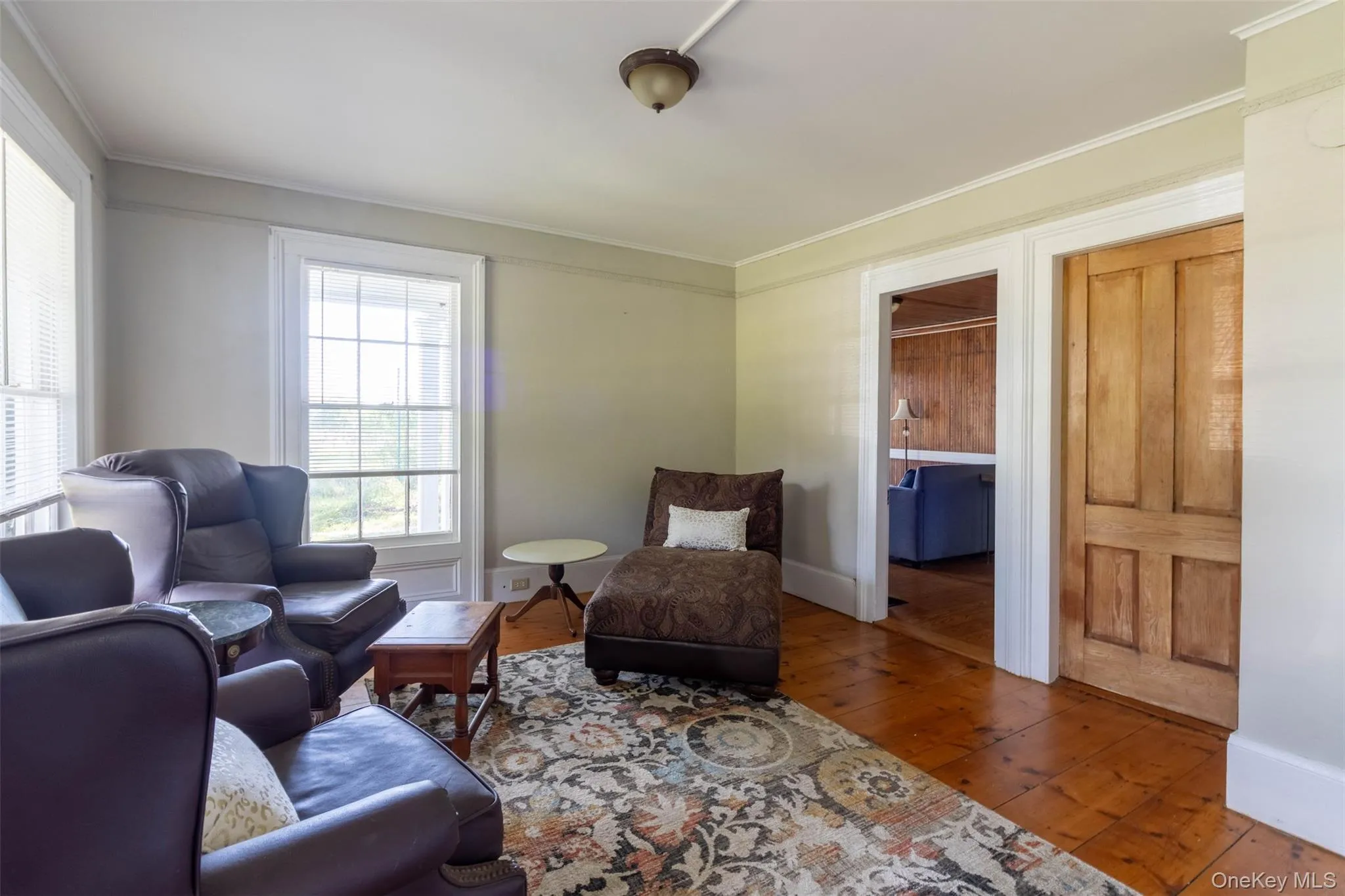 Living area featuring wood-type flooring and ornamental molding Living area featuring wood-type flooring and ornamental molding