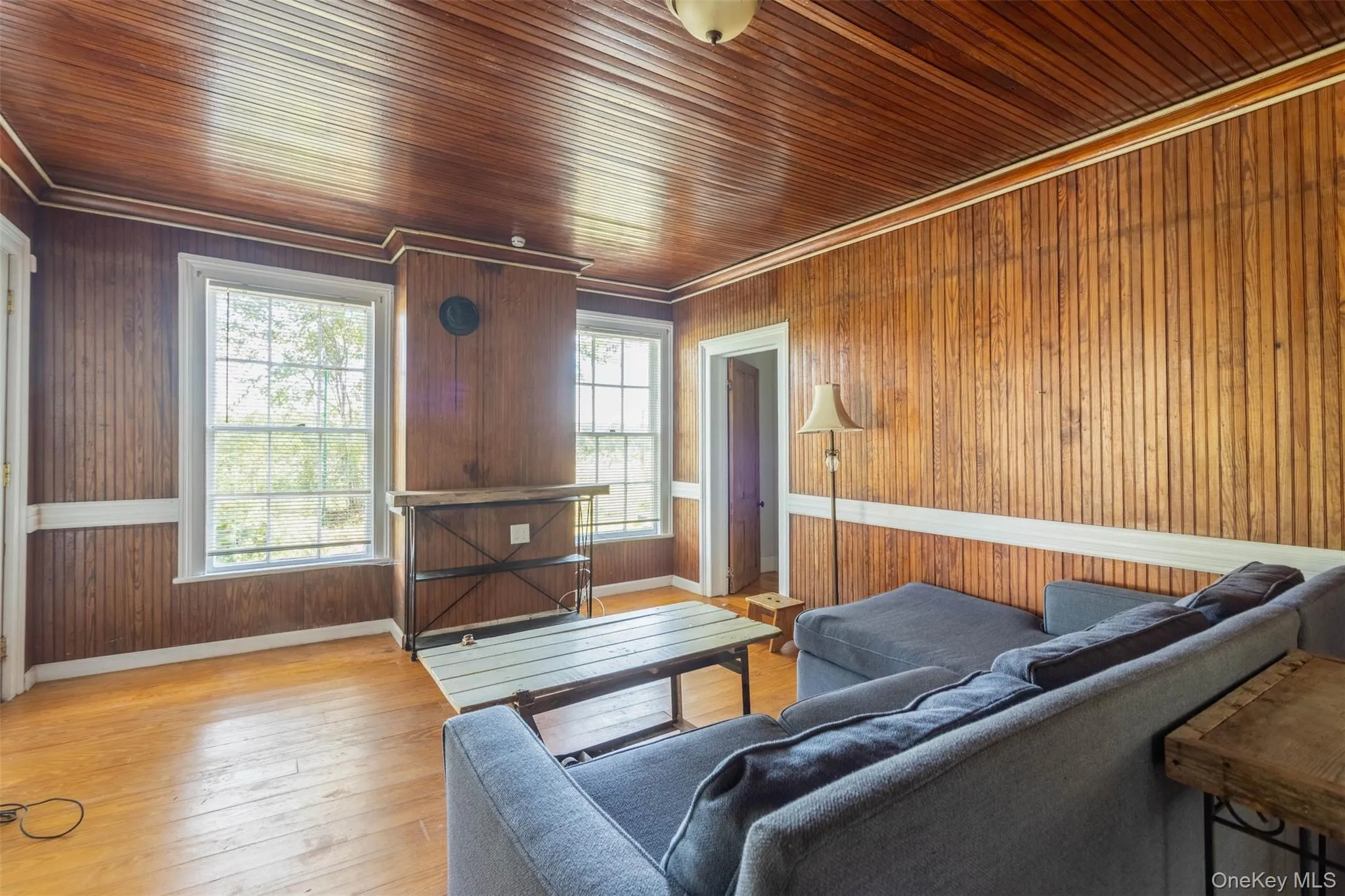 Living room featuring wood-type flooring, crown molding, and wooden walls Living room featuring wood-type flooring, crown molding, and wooden walls