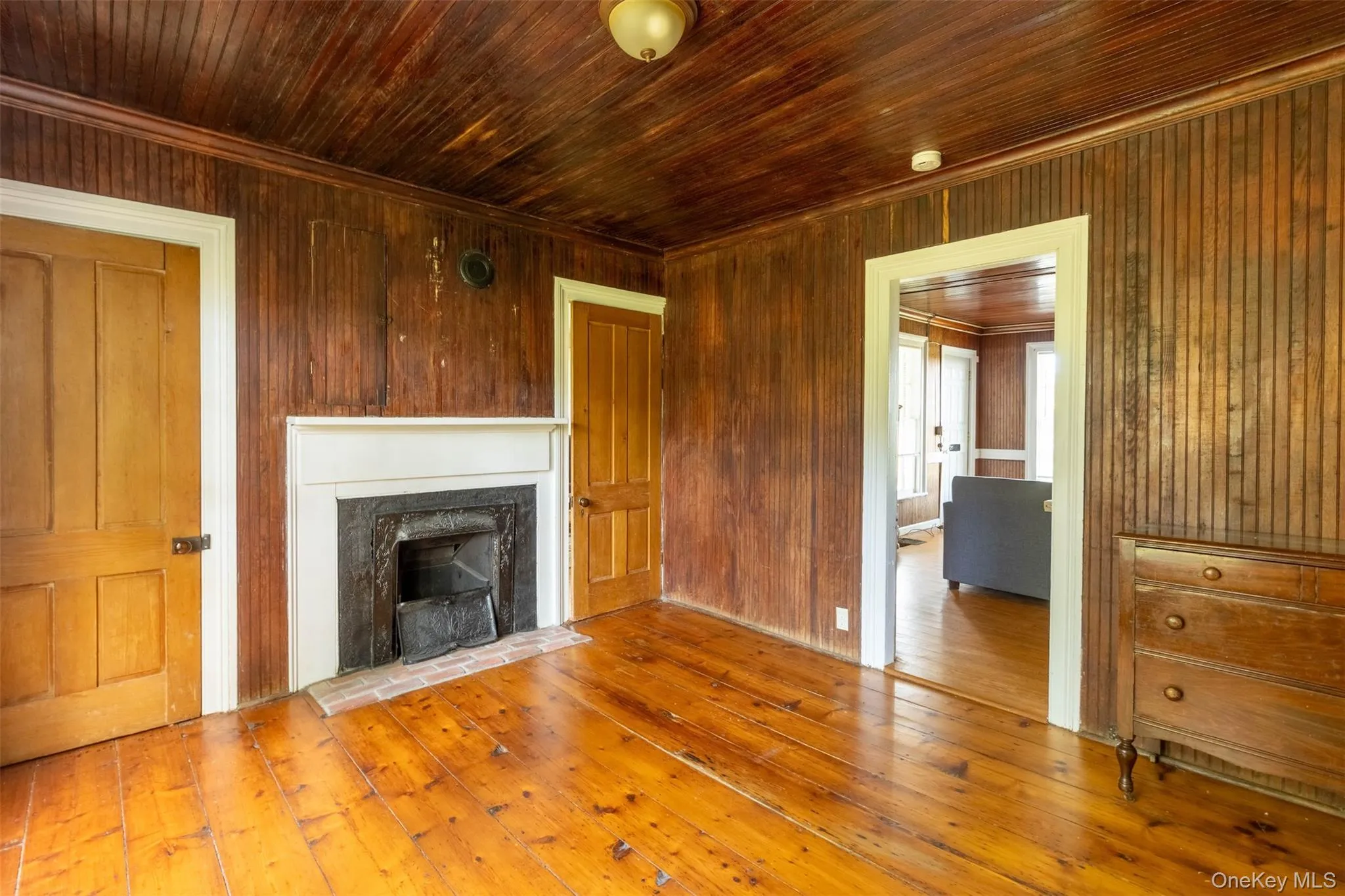 Unfurnished living room featuring hardwood / wood-style flooring, a fireplace, wood ceiling, crown molding, and wood walls Unfurnished living room featuring hardwood / wood-style flooring, a fireplace, wood ceiling, crown molding, and wood walls