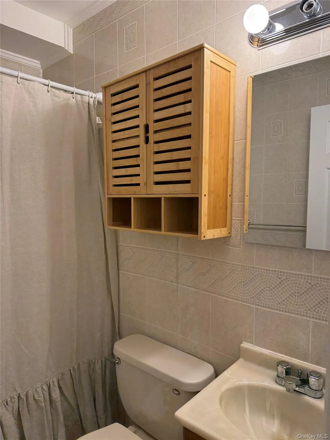 Full bath featuring tile walls, vanity, tasteful backsplash, and a shower with shower curtain Full bath featuring tile walls, vanity, tasteful backsplash, and a shower with shower curtain