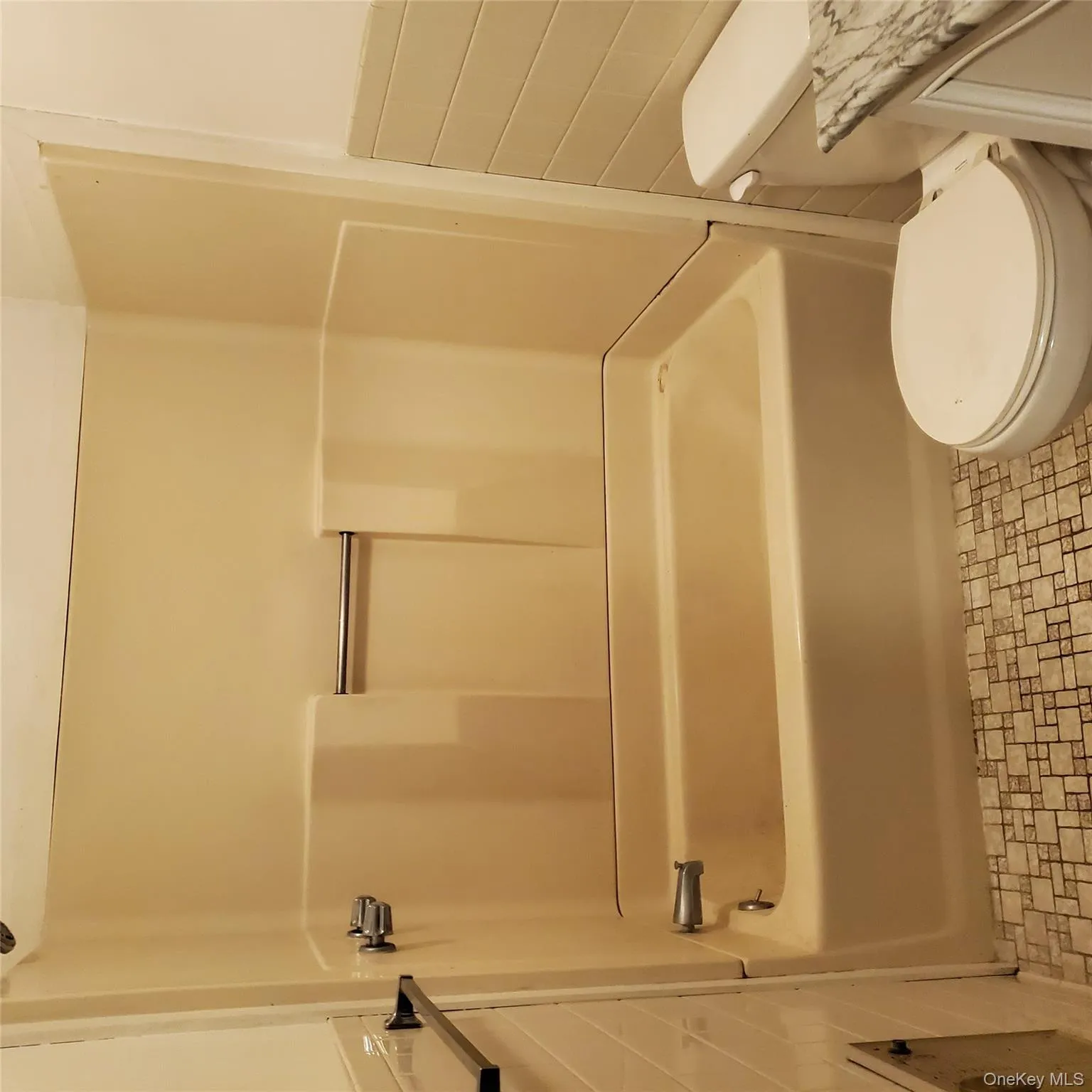 Full bath with tile walls, vanity, bathing tub / shower combination, and wainscoting Full bath with tile walls, vanity, bathing tub / shower combination, and wainscoting