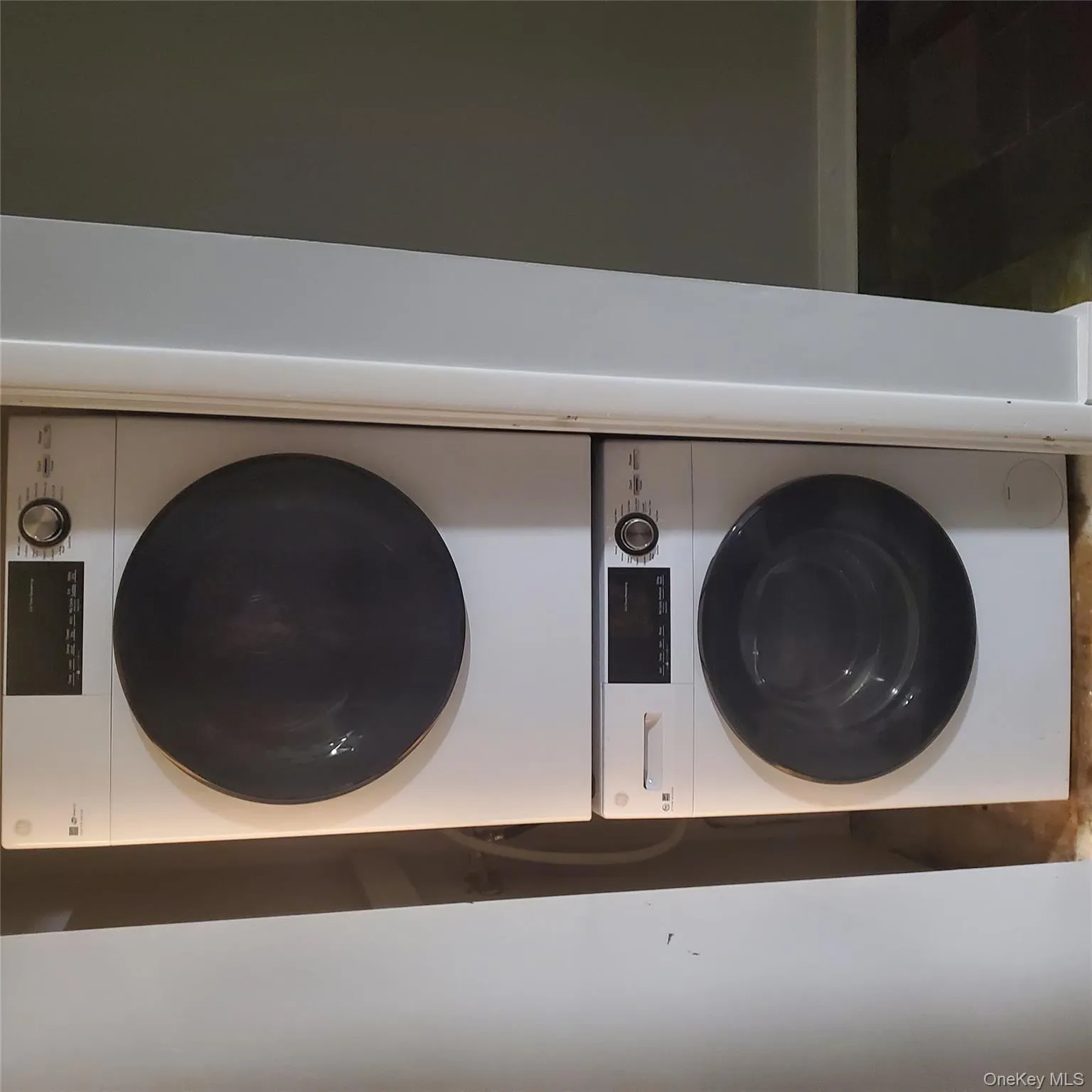 Laundry area featuring stacked washer and clothes dryer and tile patterned flooring Laundry area featuring stacked washer and clothes dryer and tile patterned flooring