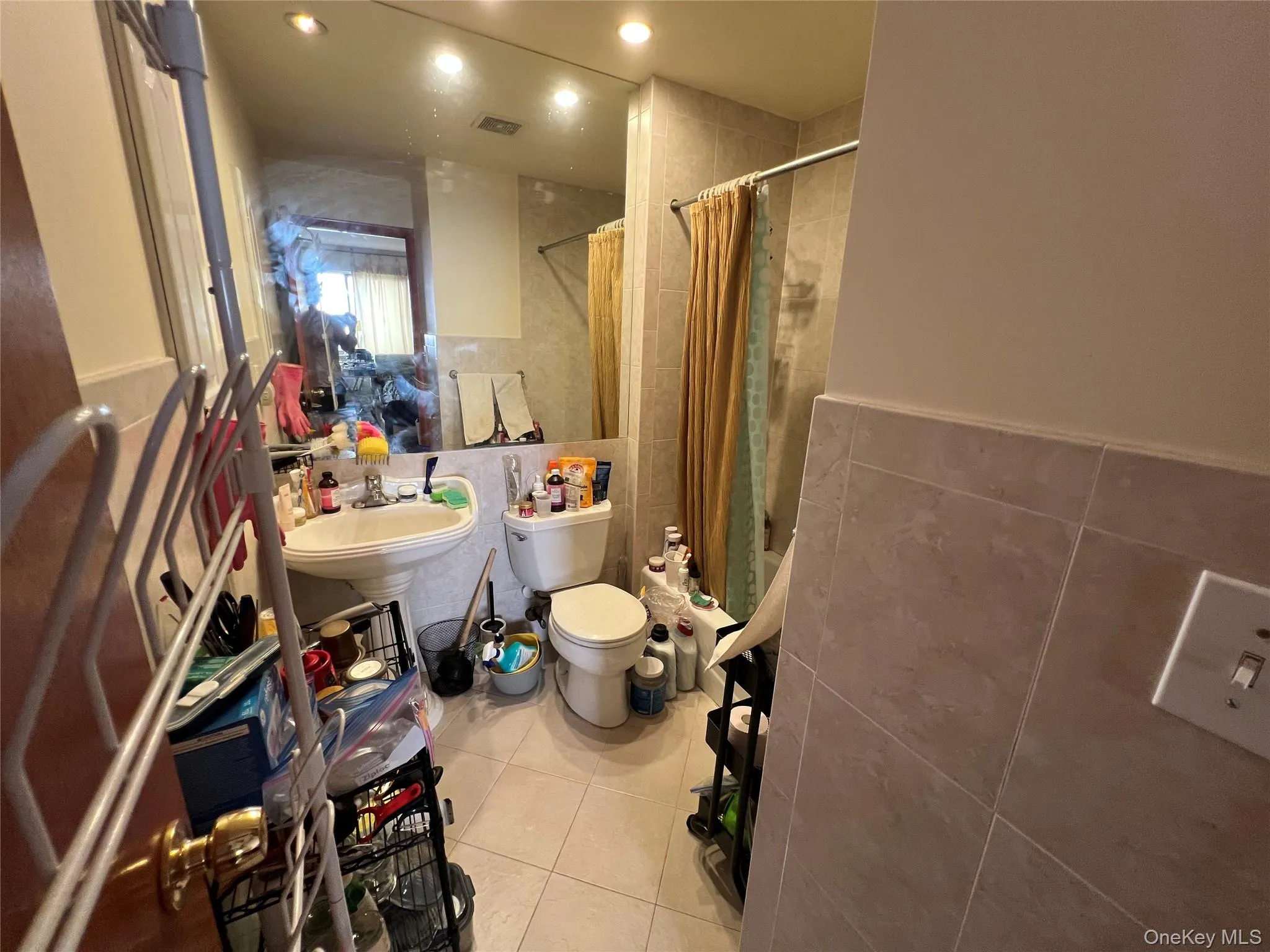 Bathroom with tile walls, light tile patterned floors, tiled shower / bath, and wainscoting Bathroom with tile walls, light tile patterned floors, tiled shower / bath, and wainscoting
