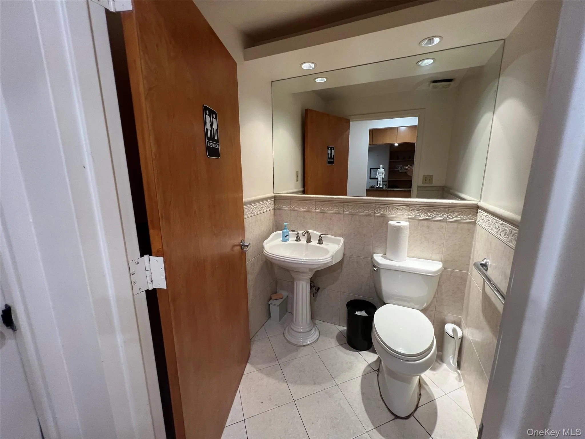 Half bathroom featuring light tile patterned flooring, tile walls, wainscoting, and recessed lighting Half bathroom featuring light tile patterned flooring, tile walls, wainscoting, and recessed lighting