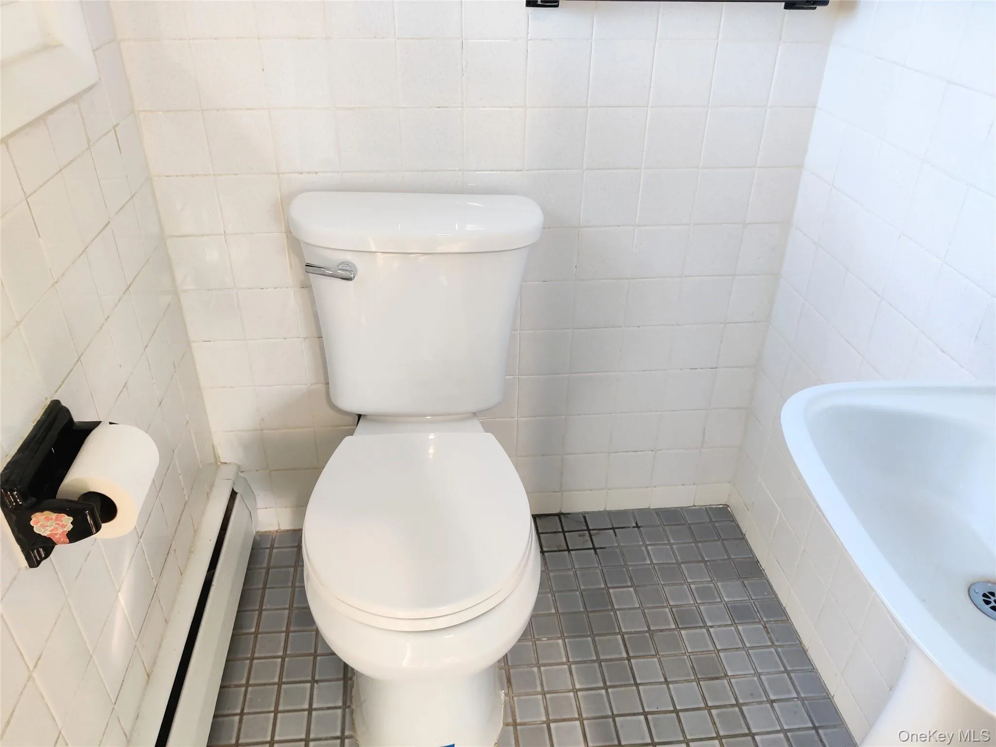 Half bath featuring a baseboard radiator, tile patterned floors, and tile walls Half bath featuring a baseboard radiator, tile patterned floors, and tile walls