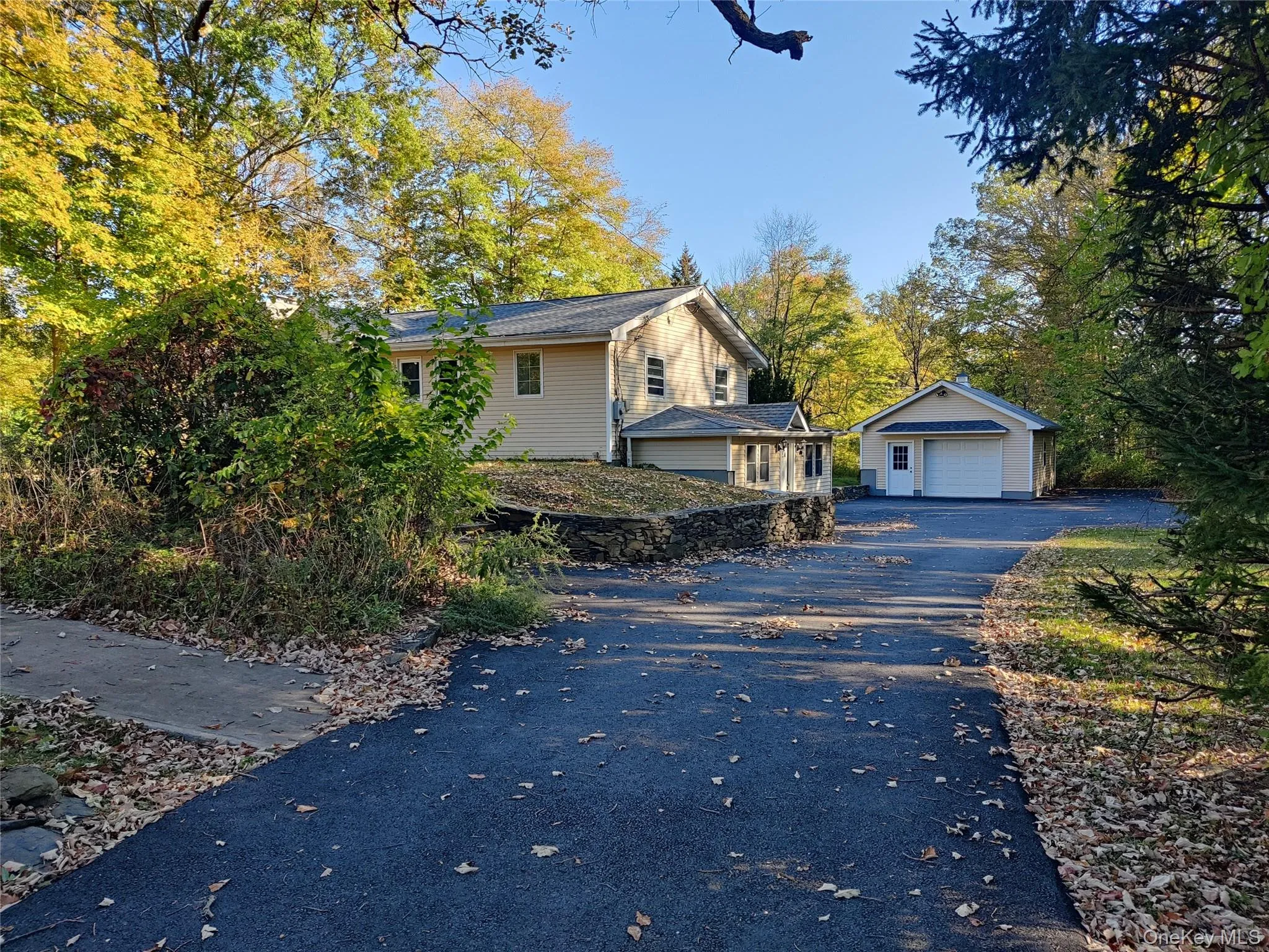 View of front facade featuring an outbuilding, a garage, and asphalt driveway View of front facade featuring an outbuilding, a garage, and asphalt driveway