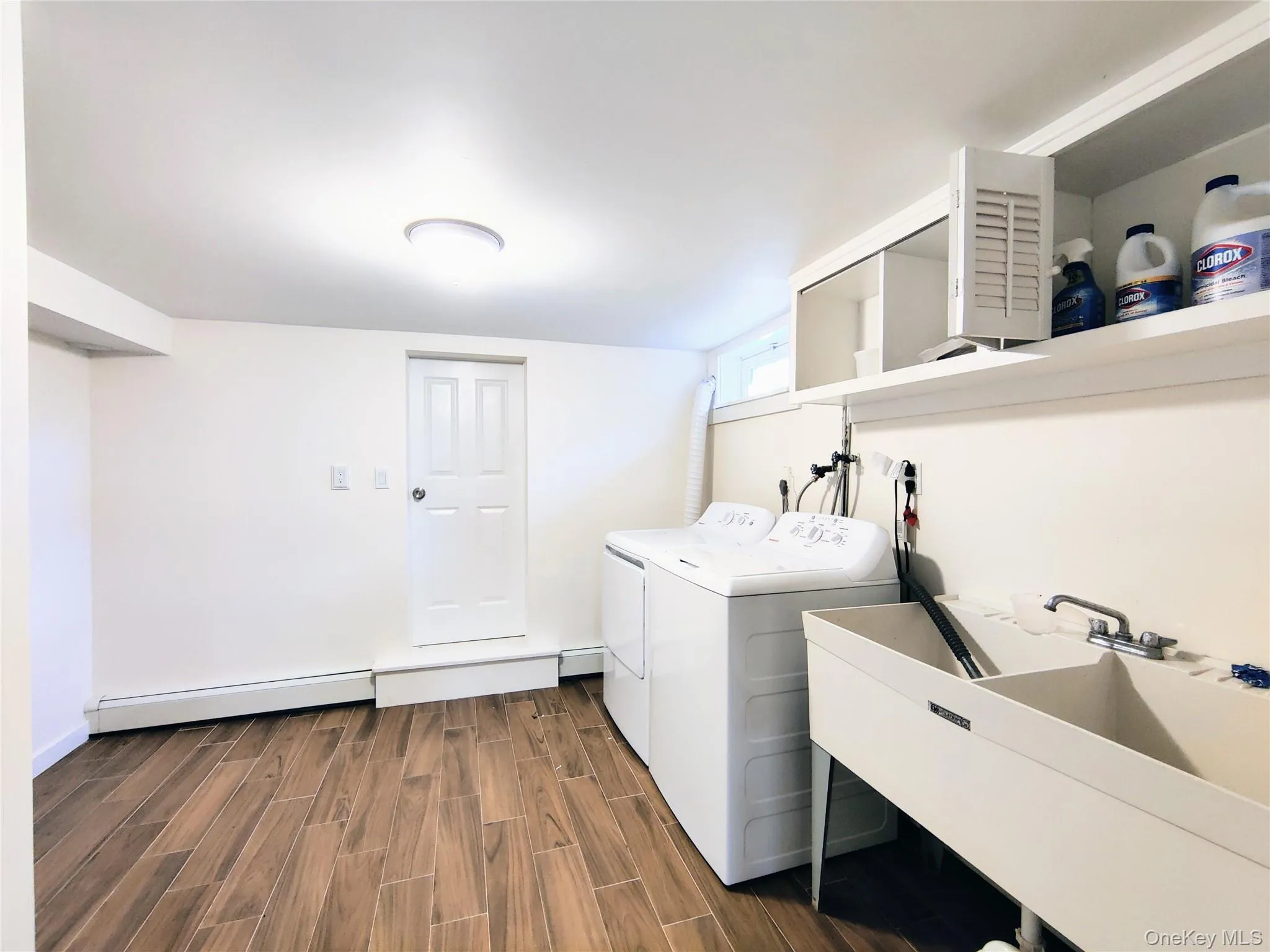 Laundry room with wood finish floors, baseboard heating, and washing machine and clothes dryer Laundry room with wood finish floors, baseboard heating, and washing machine and clothes dryer