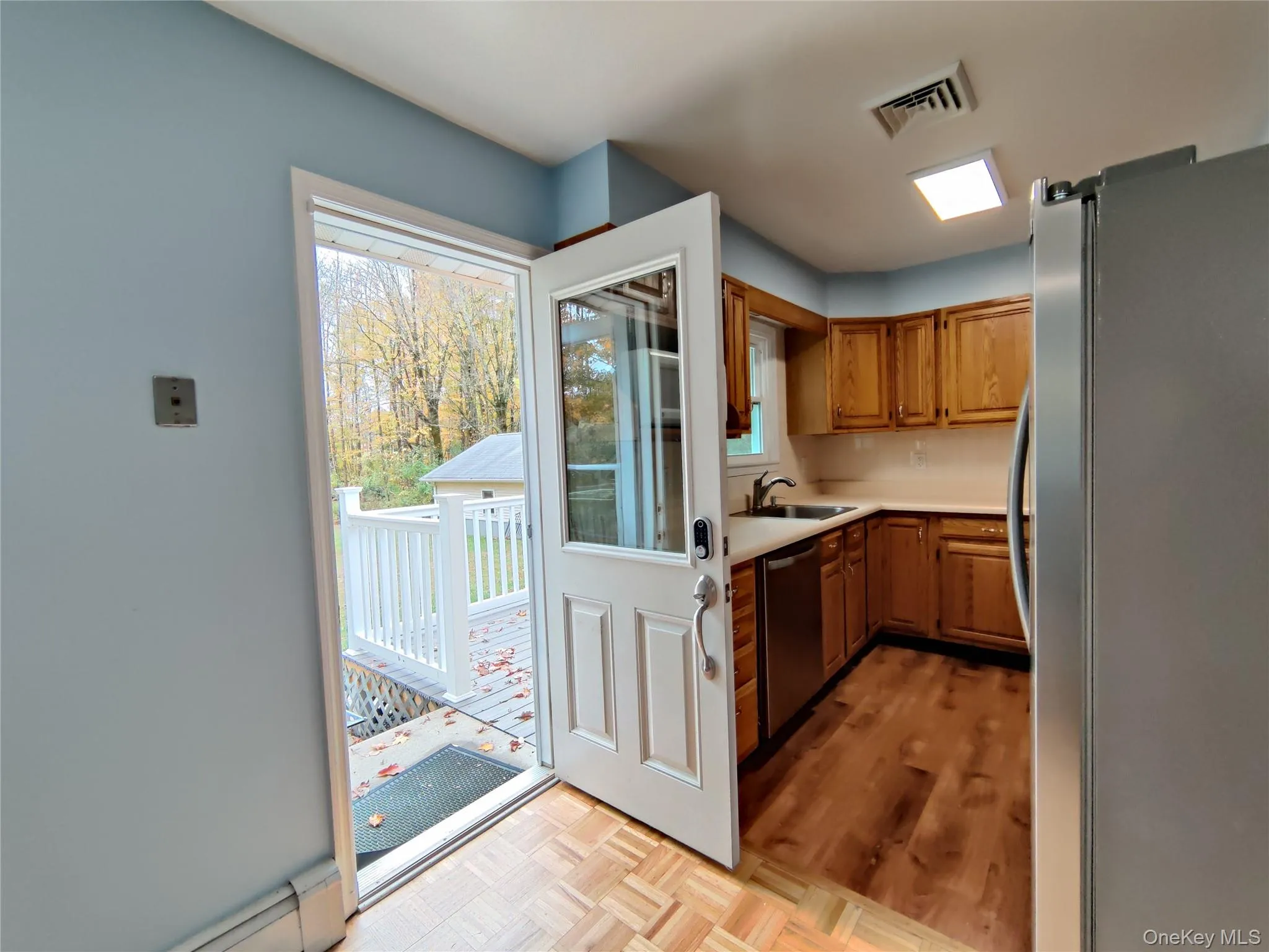 Kitchen featuring appliances with stainless steel finishes, light countertops, brown cabinets, a baseboard heating unit, and parquet floors Kitchen featuring appliances with stainless steel finishes, light countertops, brown cabinets, a baseboard heating unit, and parquet floors