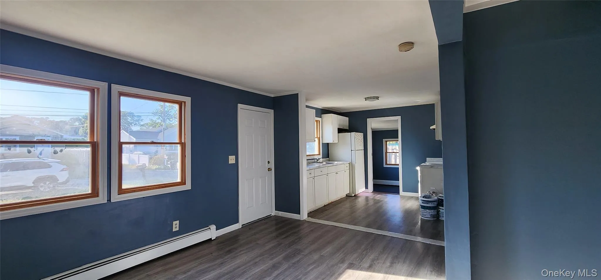 Unfurnished living room featuring dark wood-type flooring and a baseboard radiator Unfurnished living room featuring dark wood-type flooring and a baseboard radiator