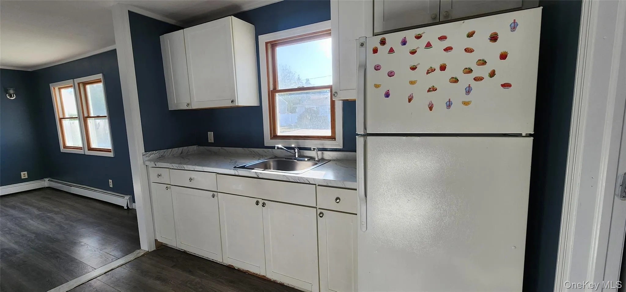 Kitchen with freestanding refrigerator, light countertops, dark wood-style flooring, plenty of natural light, and crown molding Kitchen with freestanding refrigerator, light countertops, dark wood-style flooring, plenty of natural light, and crown molding