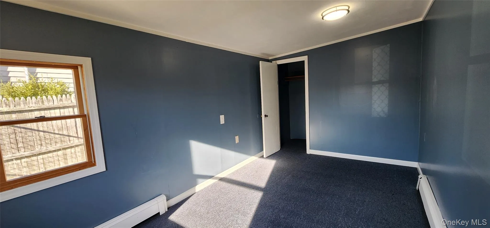 Unfurnished room featuring dark carpet, a baseboard radiator, and ornamental molding Unfurnished room featuring dark carpet, a baseboard radiator, and ornamental molding