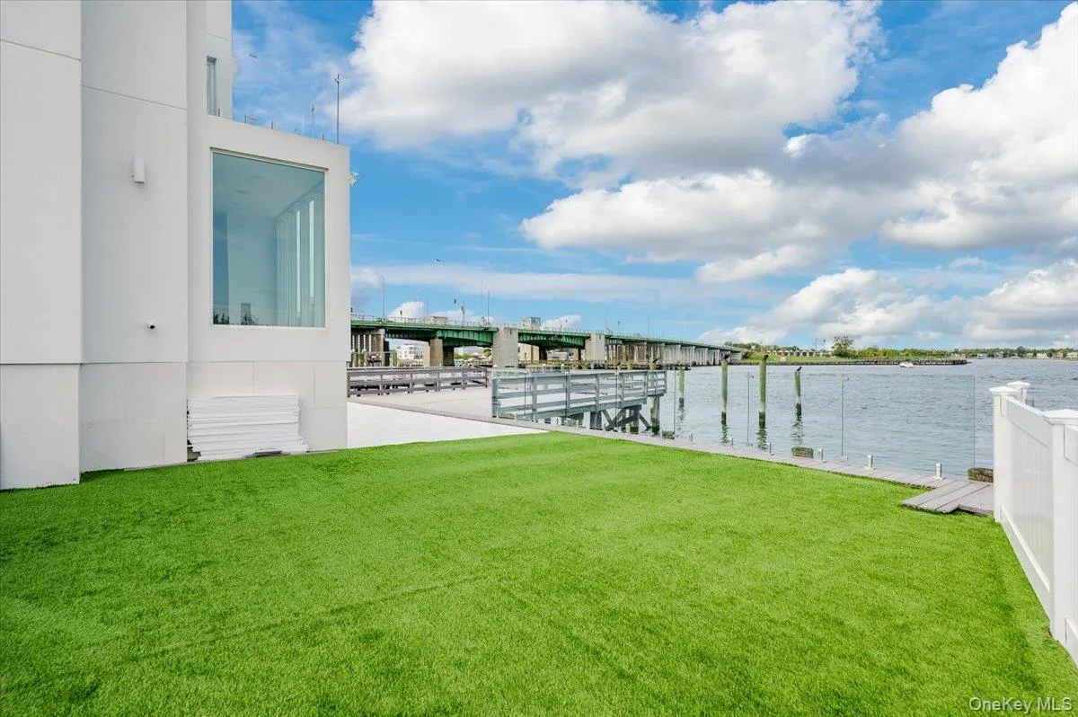 View of green lawn with a water view and a dock View of green lawn with a water view and a dock