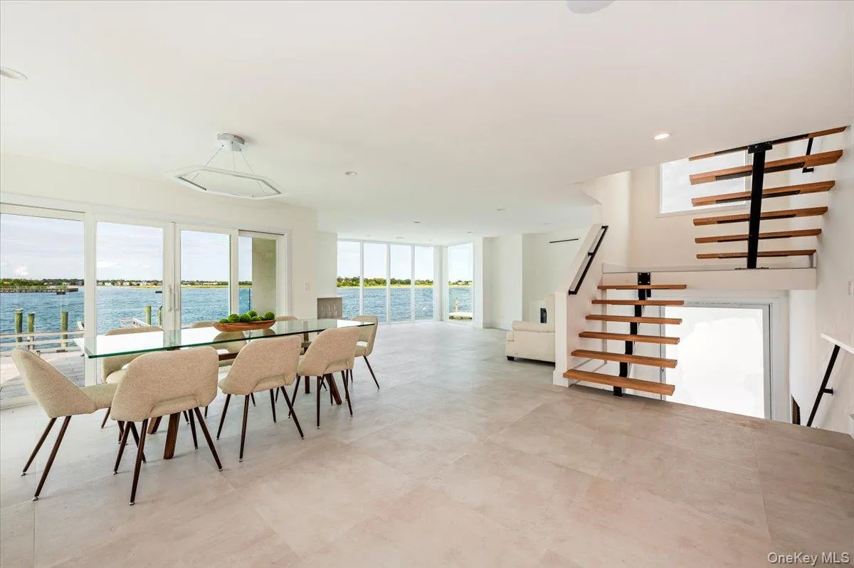 Dining space featuring a water view, plenty of natural light, recessed lighting, expansive windows, and stairway Dining space featuring a water view, plenty of natural light, recessed lighting, expansive windows, and stairway