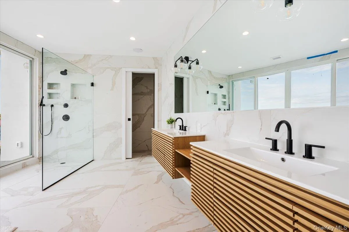 Full bath with stone wall, two vanities, light marble finish flooring, tile walls, and a marble finish shower Full bath with stone wall, two vanities, light marble finish flooring, tile walls, and a marble finish shower