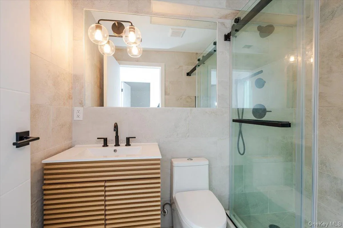 Bathroom with tile walls, vanity, a shower stall, and decorative backsplash Bathroom with tile walls, vanity, a shower stall, and decorative backsplash