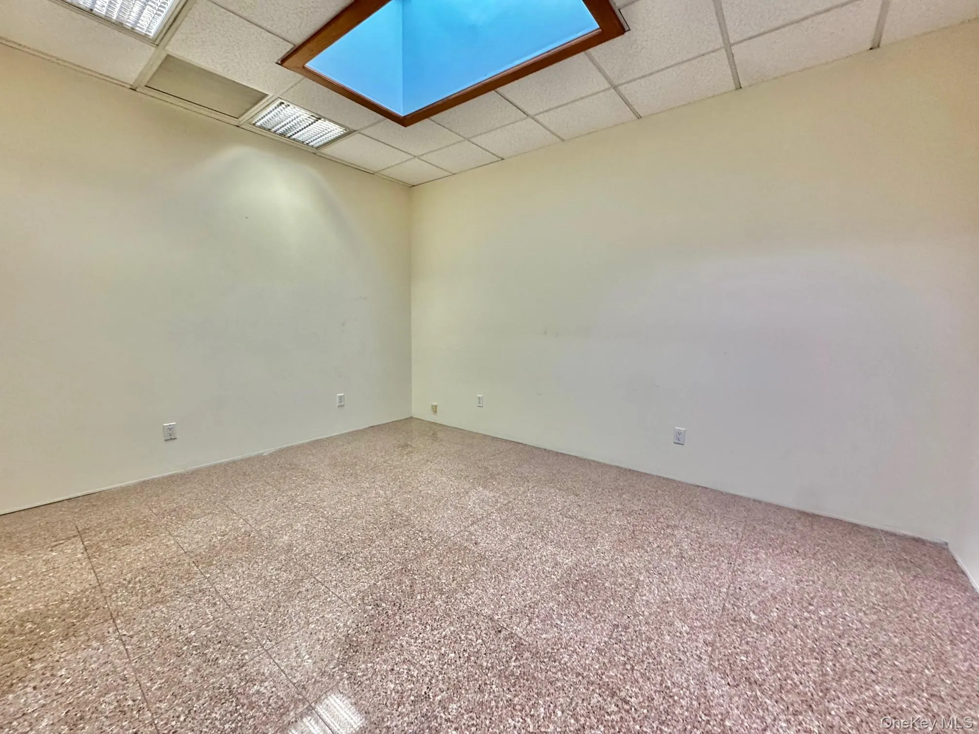 Unfurnished room featuring a drop ceiling and granite tiled floors Unfurnished room featuring a drop ceiling and granite tiled floors