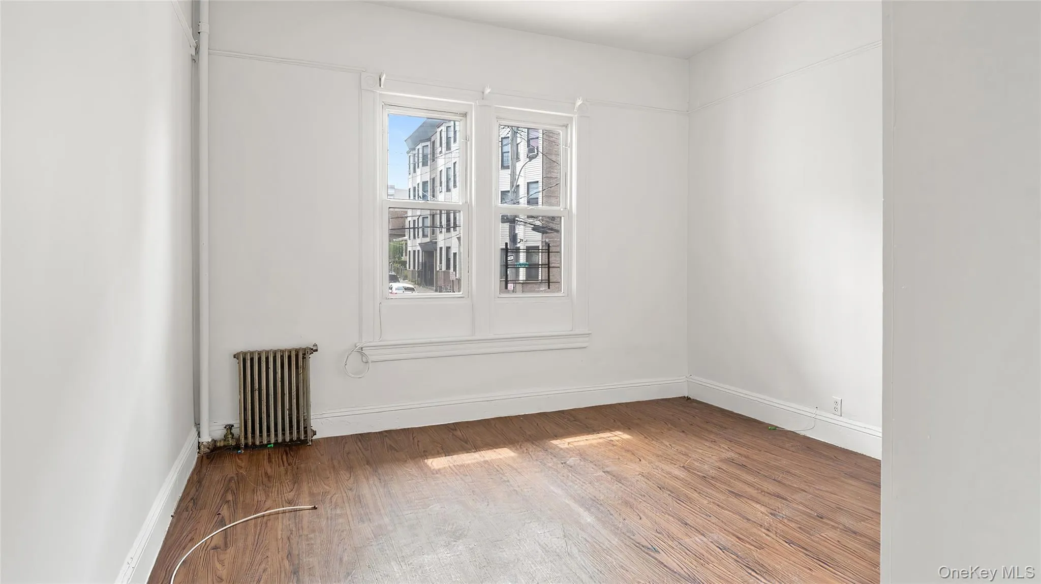 Unfurnished room featuring wood finished floors and radiator heating unit Unfurnished room featuring wood finished floors and radiator heating unit