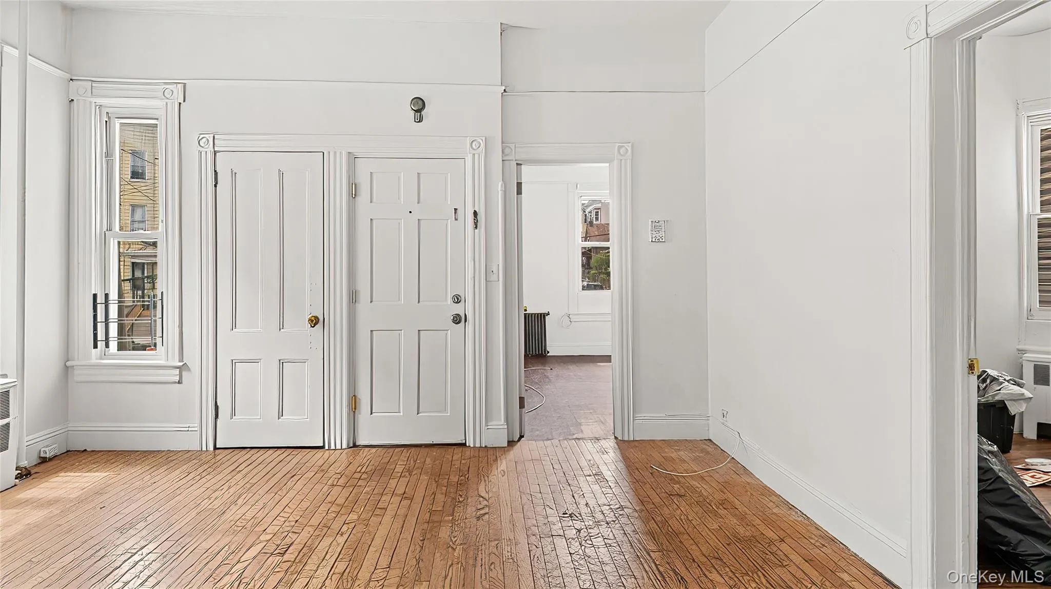 Unfurnished bedroom featuring light wood-type flooring, a closet, radiator, and radiator heating unit Unfurnished bedroom featuring light wood-type flooring, a closet, radiator, and radiator heating unit