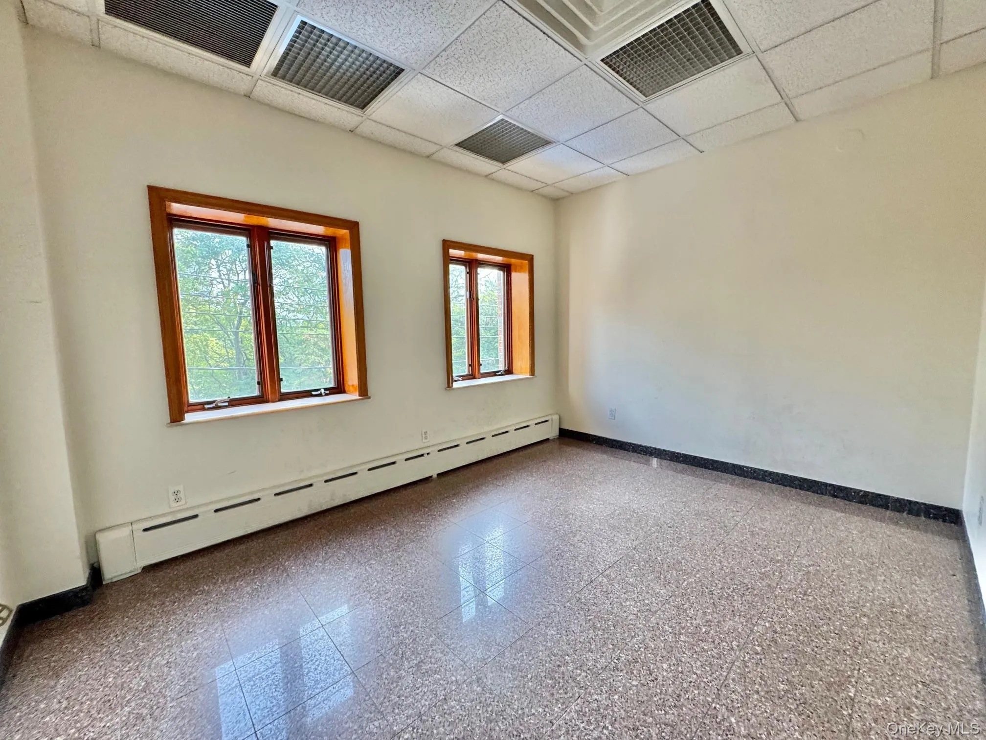 Empty room with baseboard heating and a drop ceiling Empty room with baseboard heating and a drop ceiling