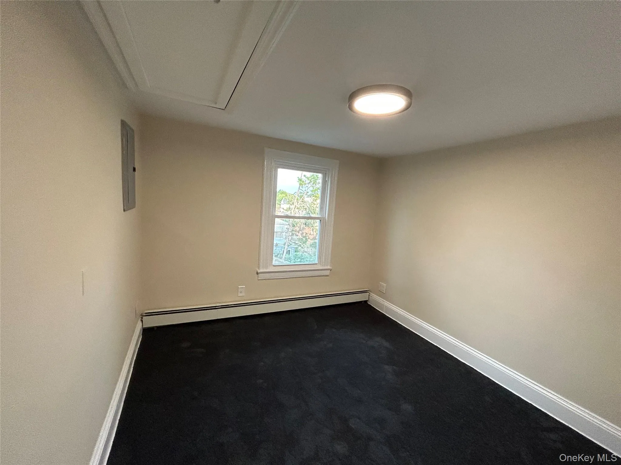 Spare room with dark carpet, a baseboard heating unit, and electric panel Spare room with dark carpet, a baseboard heating unit, and electric panel