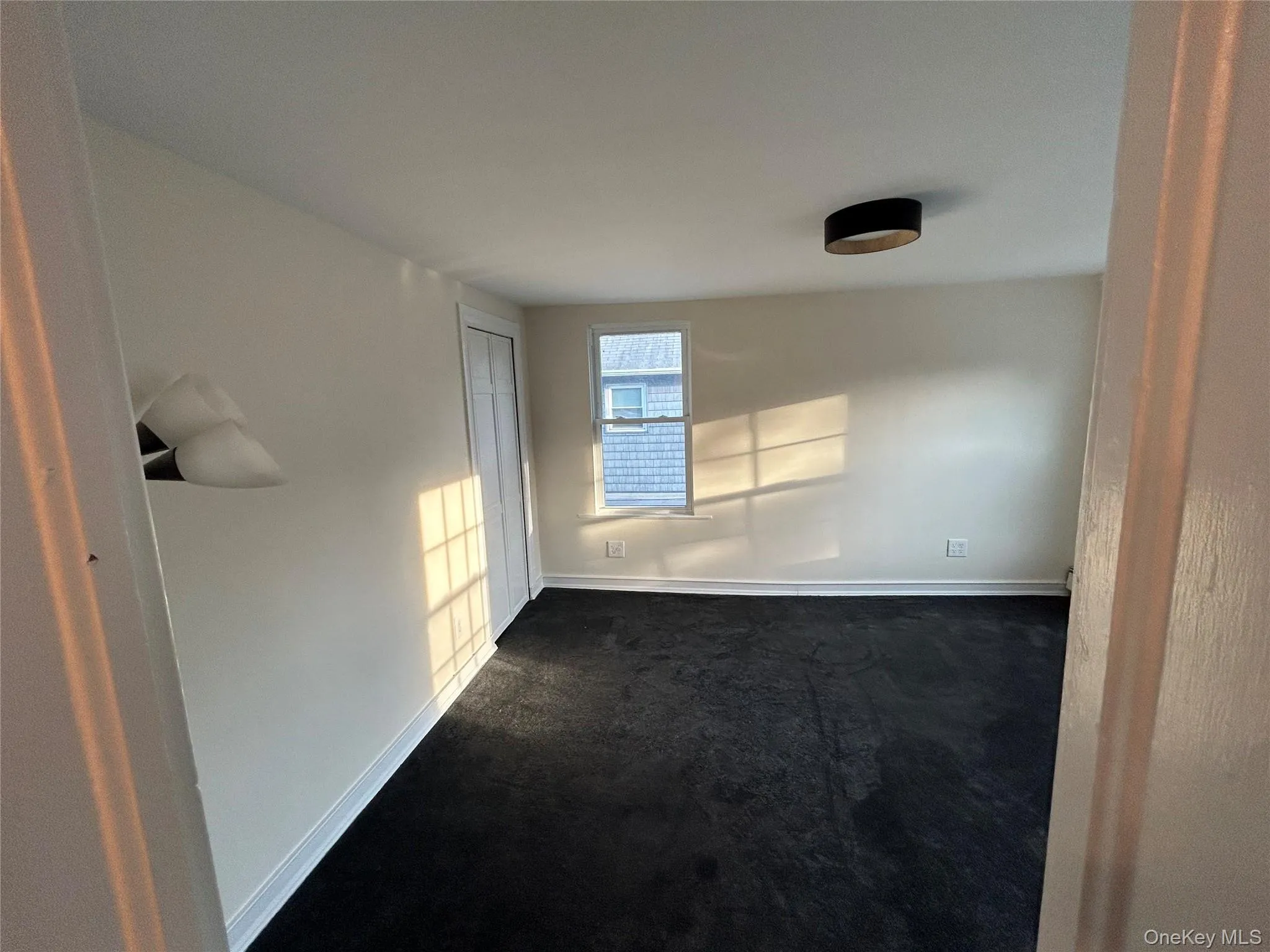 Unfurnished room featuring baseboards and dark colored carpet Unfurnished room featuring baseboards and dark colored carpet