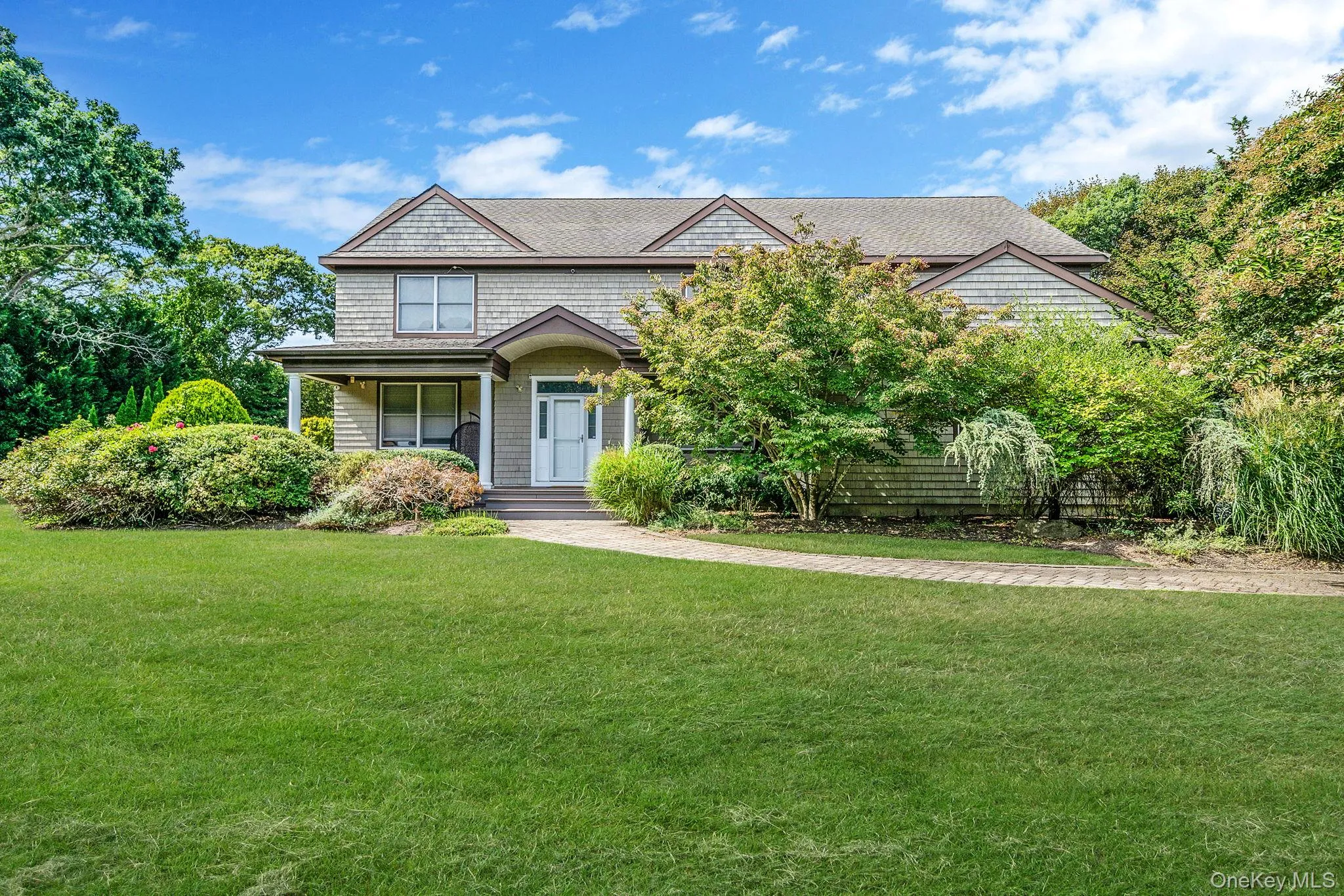 Shingle-style home with a front lawn and covered porch Shingle-style home with a front lawn and covered porch