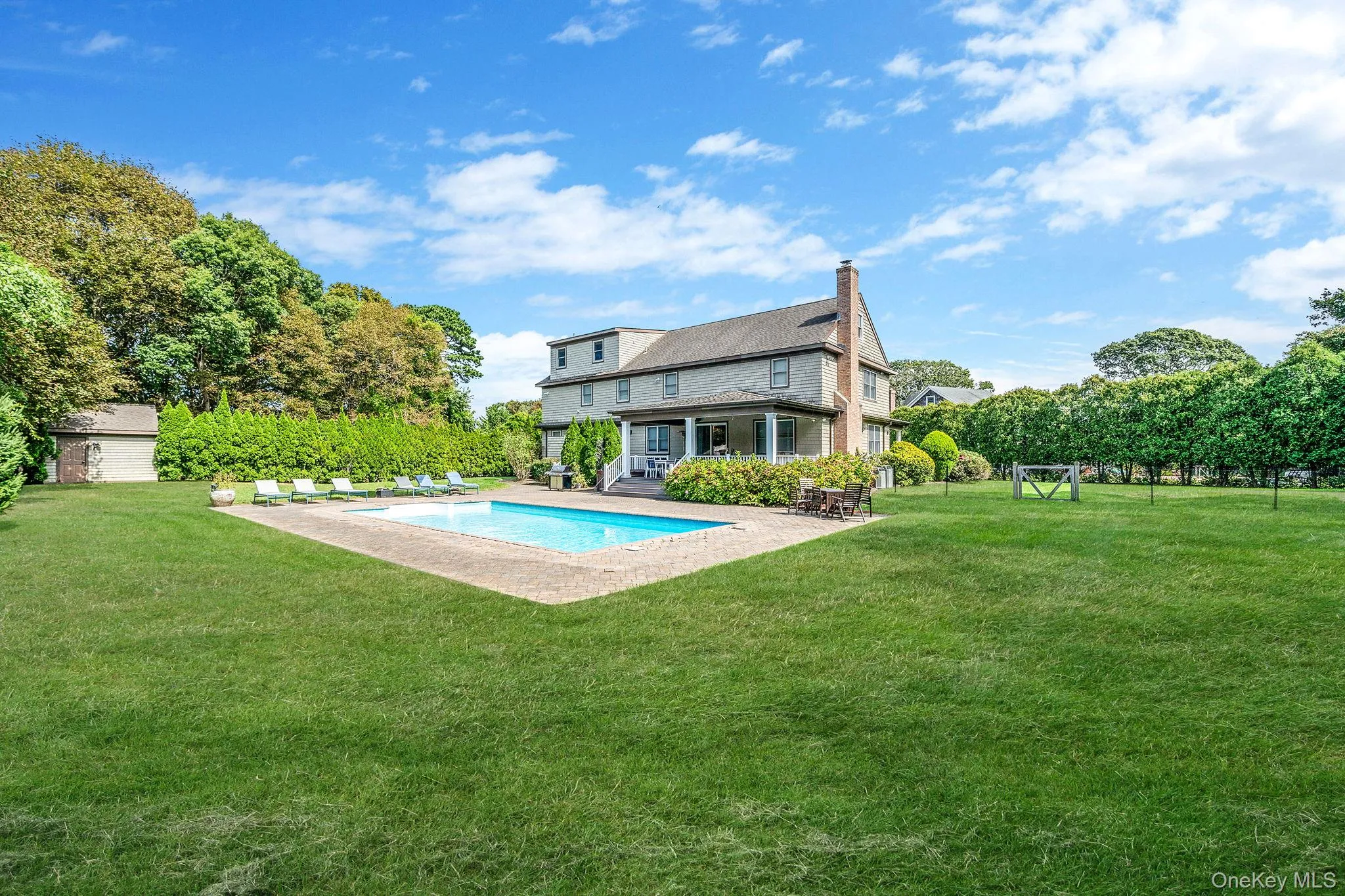 Rear view of house with a yard, a patio area, a chimney, and view of scattered trees Rear view of house with a yard, a patio area, a chimney, and view of scattered trees