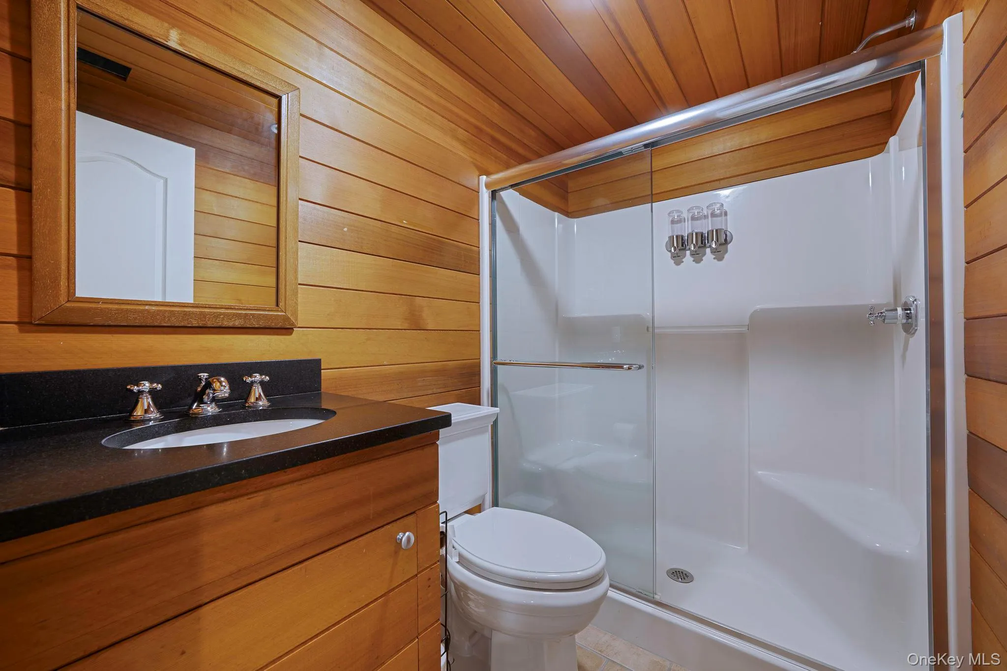 Bathroom featuring vanity, a shower stall, wooden walls, light tile patterned floors, and wooden ceiling Bathroom featuring vanity, a shower stall, wooden walls, light tile patterned floors, and wooden ceiling