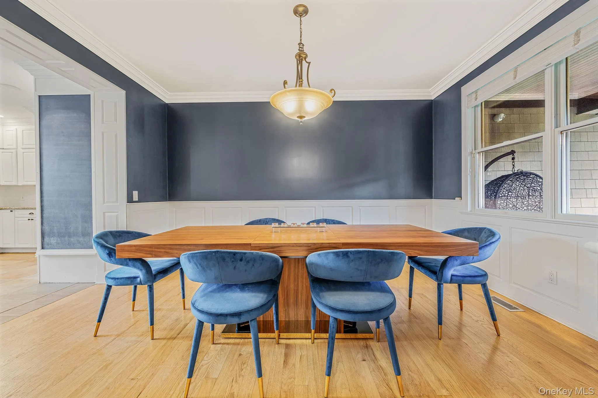 Dining space with crown molding, a decorative wall, light wood-type flooring, and wainscoting Dining space with crown molding, a decorative wall, light wood-type flooring, and wainscoting