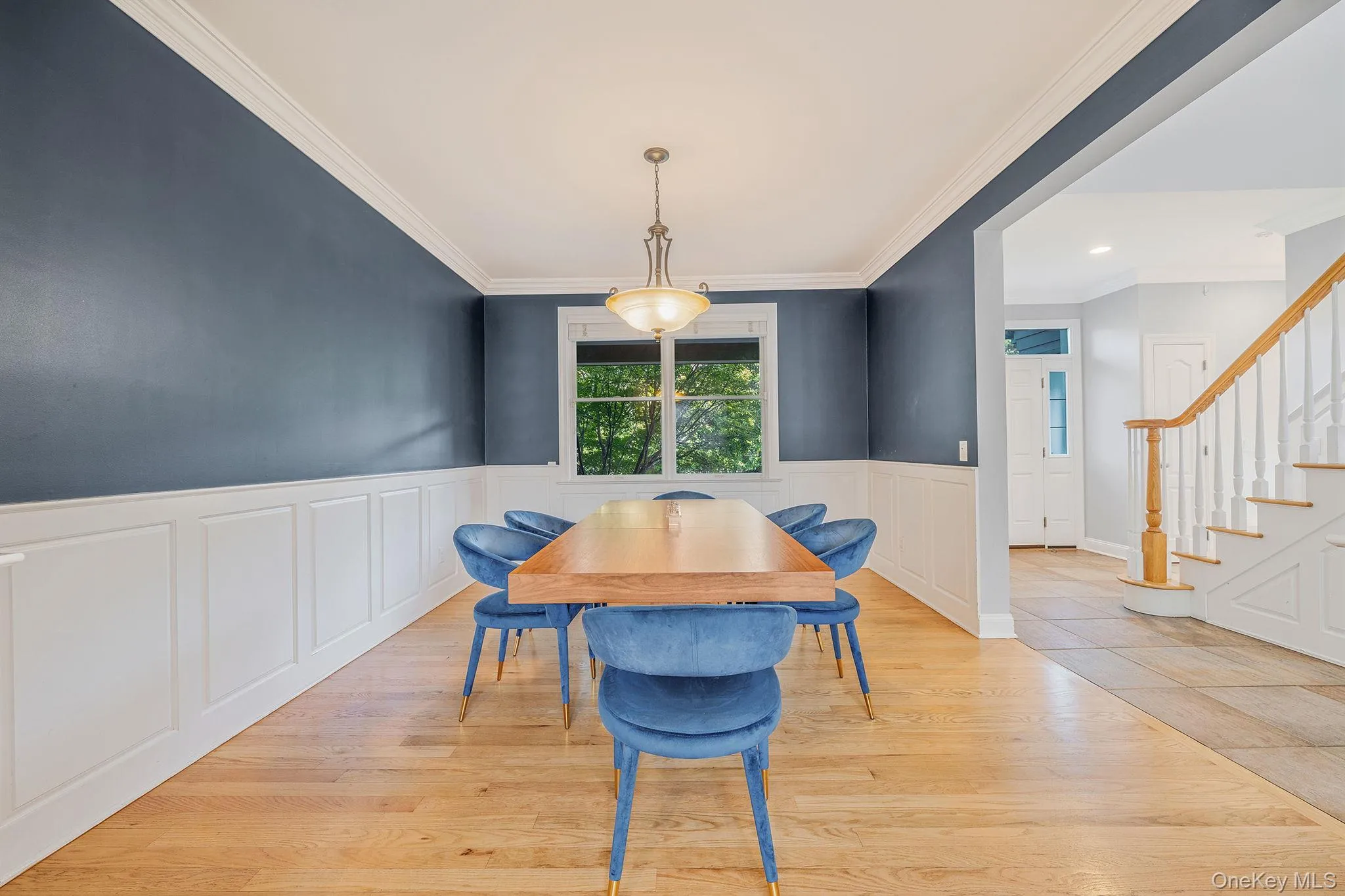 Dining room featuring stairway, wood finished floors, ornamental molding, and a wainscoted wall Dining room featuring stairway, wood finished floors, ornamental molding, and a wainscoted wall