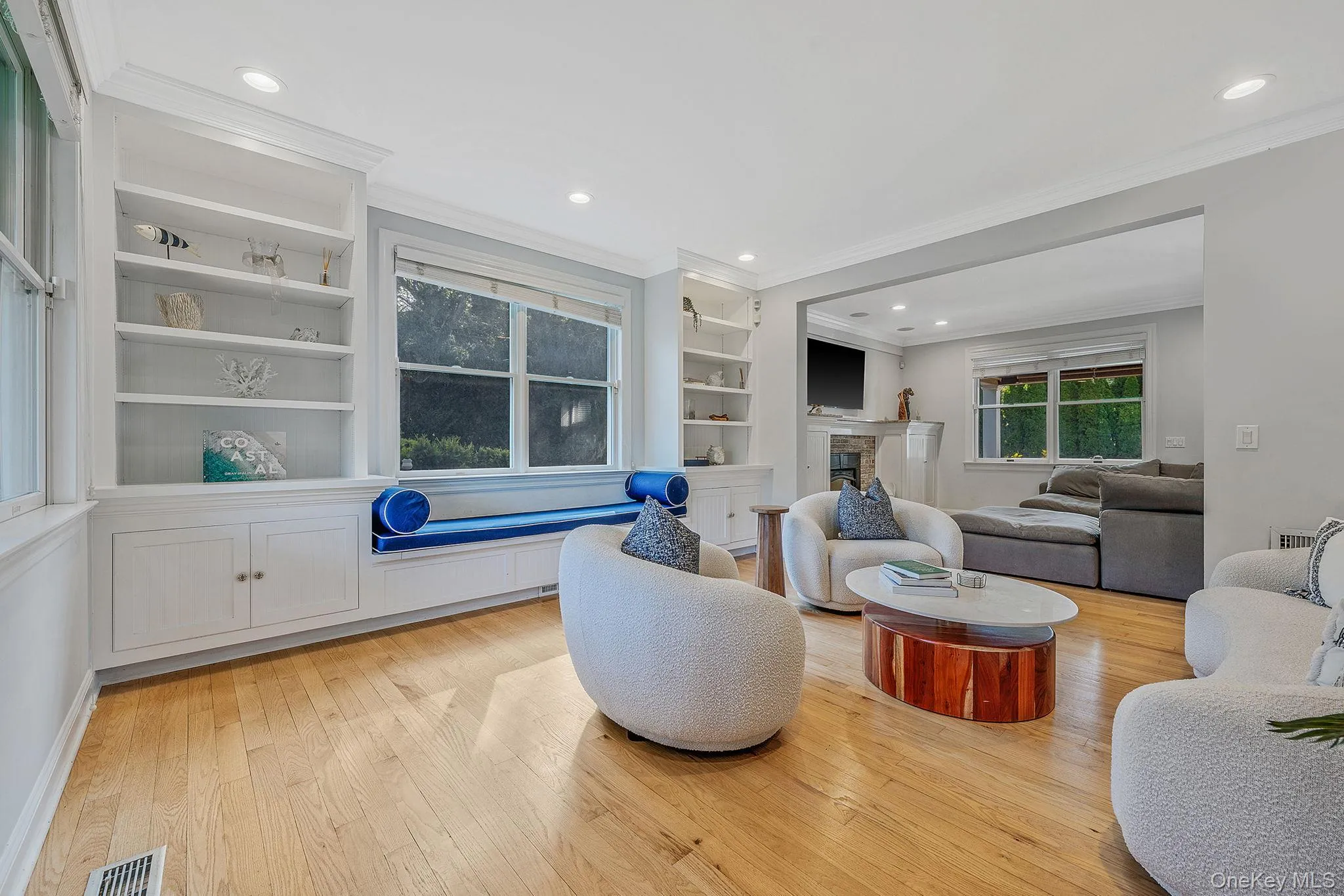 Living area with light wood finished floors, crown molding, a fireplace, recessed lighting, and built in features Living area with light wood finished floors, crown molding, a fireplace, recessed lighting, and built in features