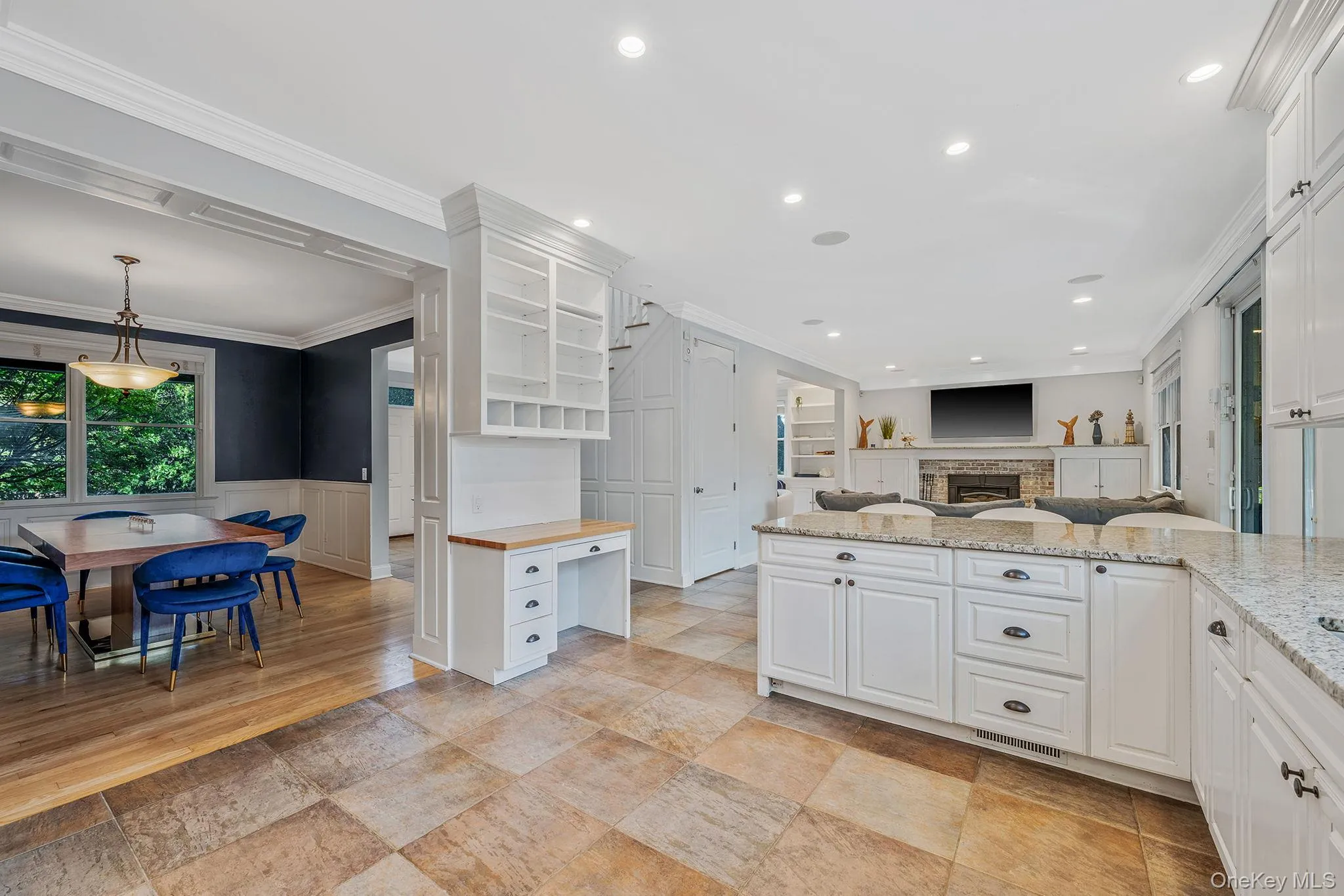 Kitchen with light stone counters, a fireplace, open floor plan, white cabinets, and crown molding Kitchen with light stone counters, a fireplace, open floor plan, white cabinets, and crown molding