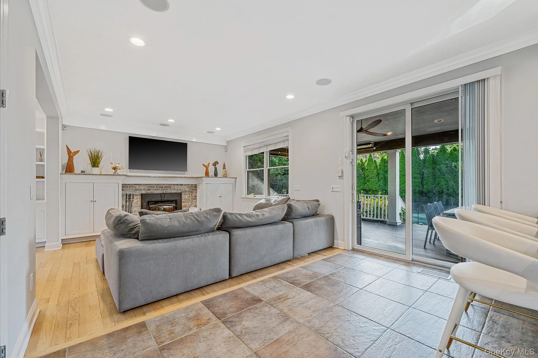 Living area with ornamental molding, recessed lighting, a brick fireplace, and light wood-style flooring Living area with ornamental molding, recessed lighting, a brick fireplace, and light wood-style flooring