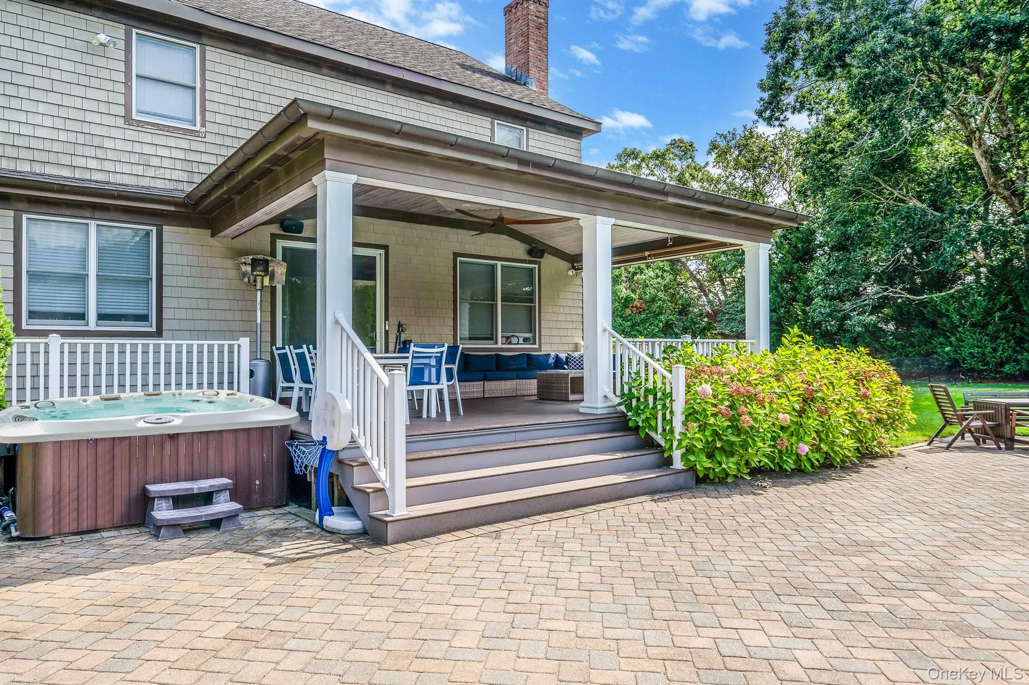 Rear view of property featuring a patio area, a hot tub, a ceiling fan, and a chimney Rear view of property featuring a patio area, a hot tub, a ceiling fan, and a chimney