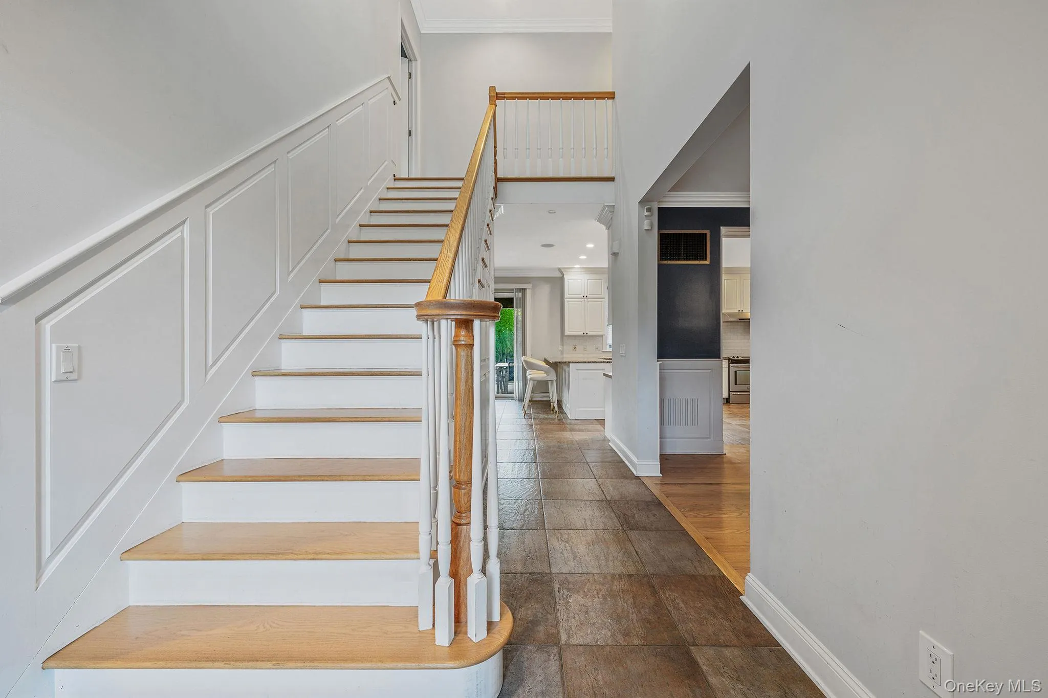 Staircase featuring a decorative wall, a wainscoted wall, and crown molding Staircase featuring a decorative wall, a wainscoted wall, and crown molding