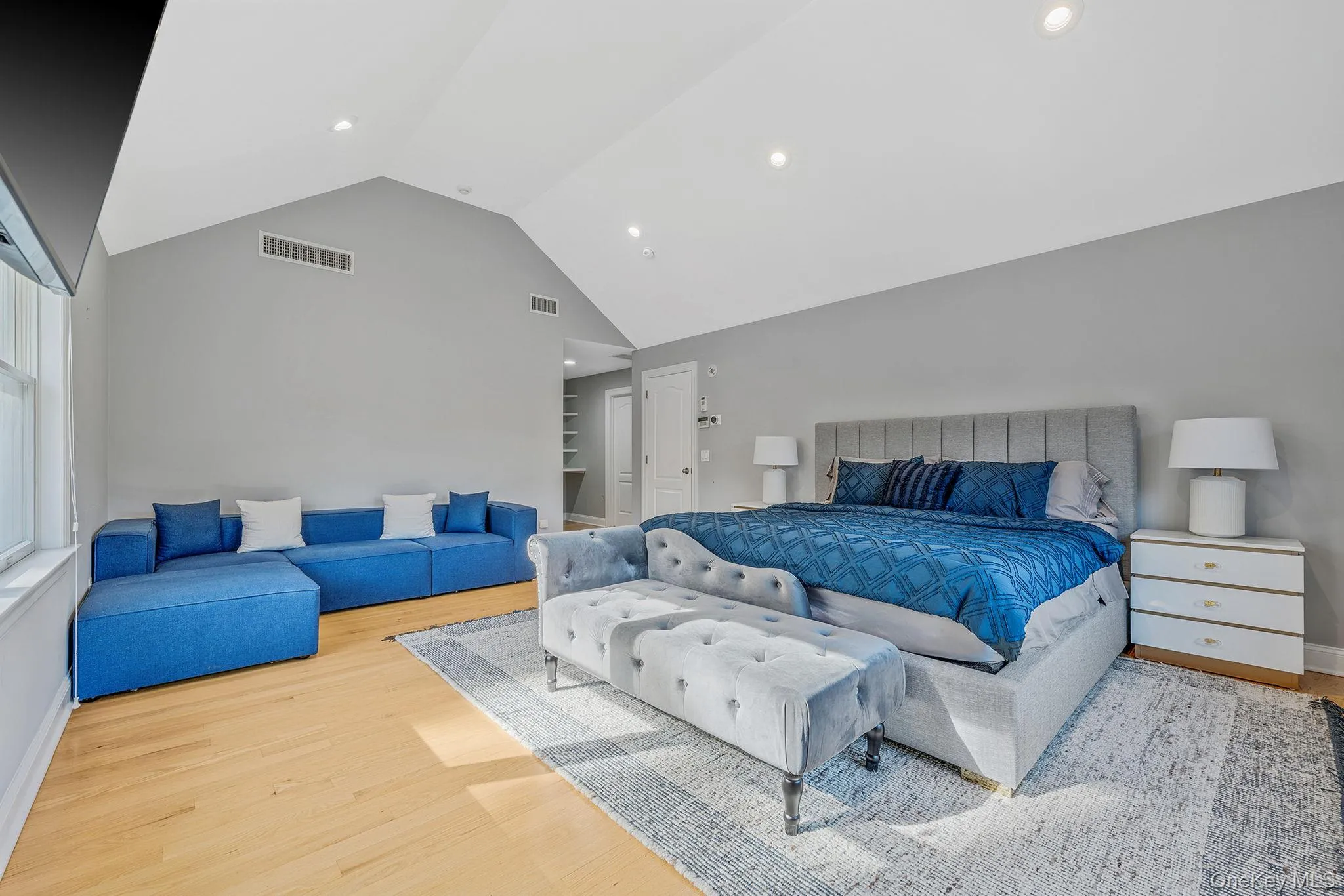 Bedroom with light wood finished floors, high vaulted ceiling, and recessed lighting Bedroom with light wood finished floors, high vaulted ceiling, and recessed lighting