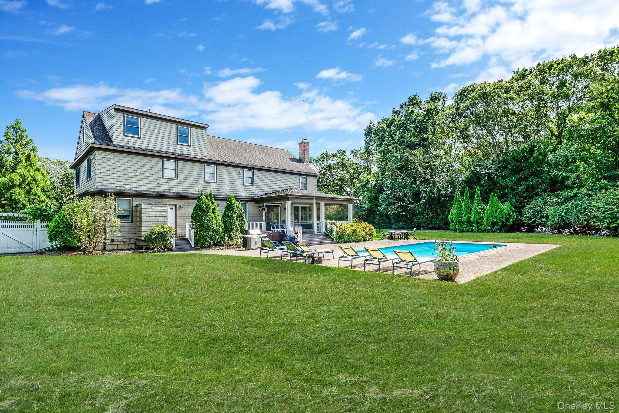 Rear view of property with a patio area, a lawn, an outdoor pool, and entry steps Rear view of property with a patio area, a lawn, an outdoor pool, and entry steps