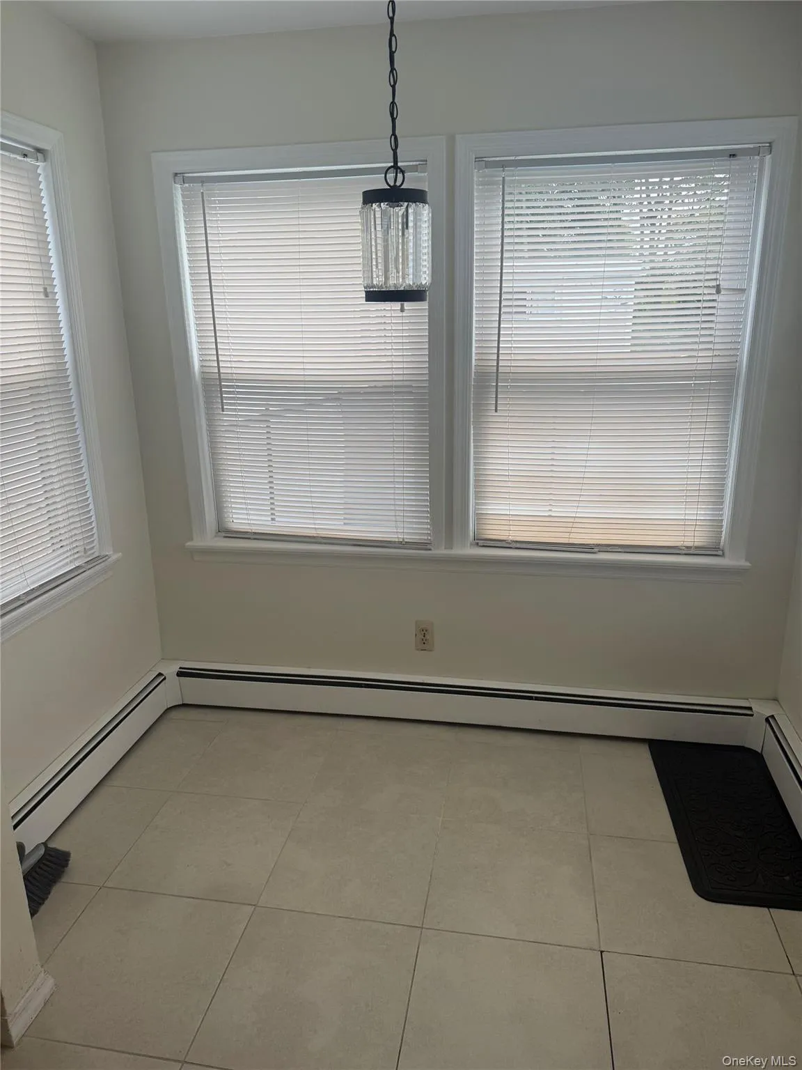 Unfurnished dining area with light tile patterned flooring and a baseboard heating unit Unfurnished dining area with light tile patterned flooring and a baseboard heating unit