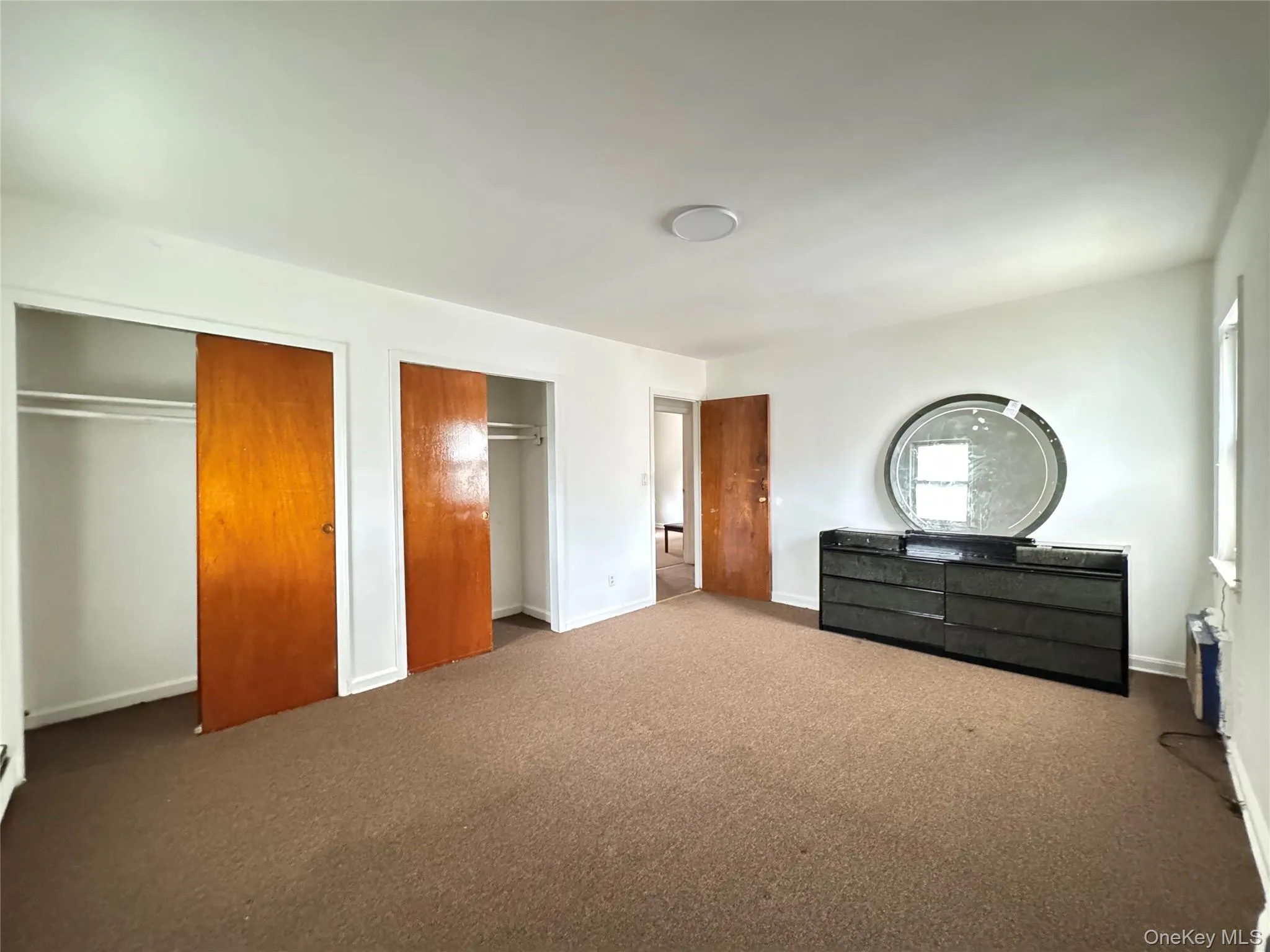 Unfurnished bedroom featuring multiple closets and carpet Unfurnished bedroom featuring multiple closets and carpet