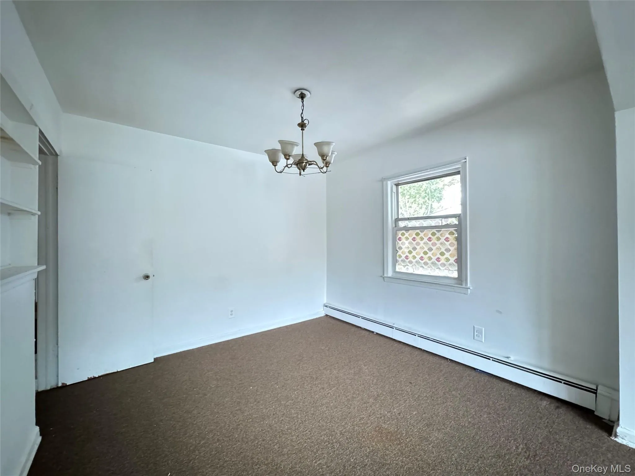 Spare room with a baseboard radiator, carpet, and a chandelier Spare room with a baseboard radiator, carpet, and a chandelier